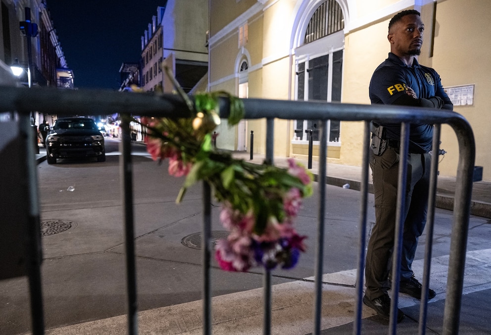 PHOTO: A member of the FBI looks on near a bouquet of flowers tied to a fence, a block from Bourbon Street, after at least 14 people were killed during a terrorist attack, January 1, 2025, in New Orleans, Louisiana.