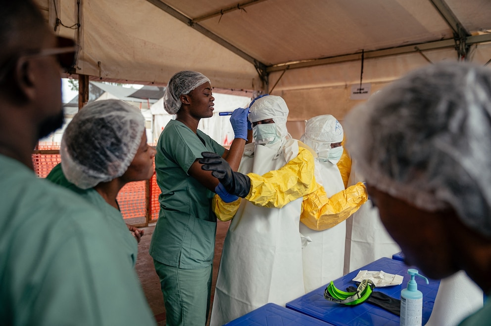 PHOTO: Healthcare workers put on personal protective equipment in the dressing area under the supervision of specialists before going to examine patients in the isolation ward at the Ebola Treatment Center in Munigi on June 2, 2026.