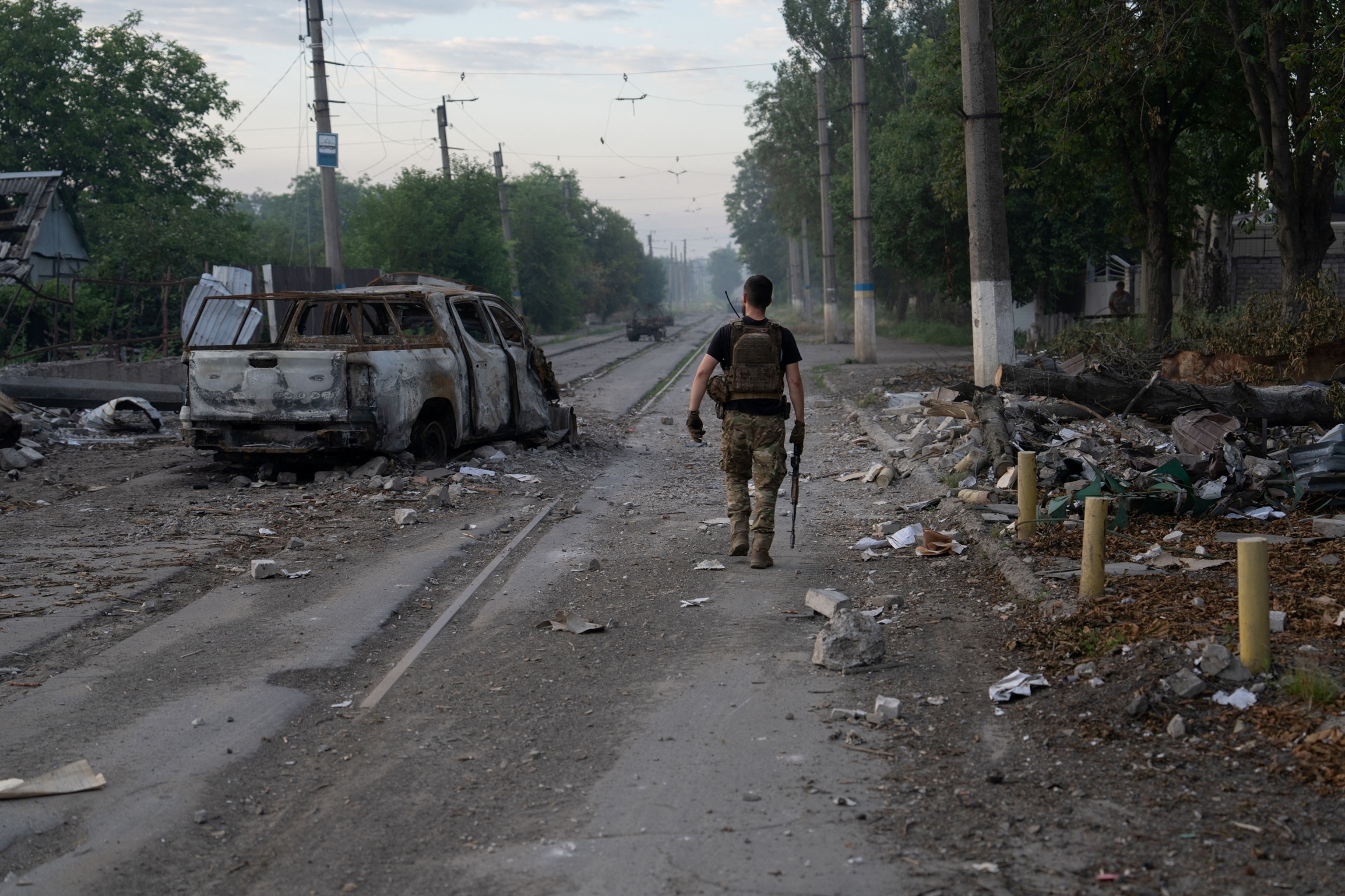 PHOTO: In this handout photograph taken on July 3, 2026 by the press service of the 93rd Kholodnyi Yar Separate Mechanized Brigade, a Ukrainian serviceman walks past a burned-out car on the street in Druzhkivka, Donetsk region.