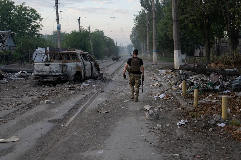 PHOTO: In this handout photograph taken on July 3, 2026 by the press service of the 93rd Kholodnyi Yar Separate Mechanized Brigade, a Ukrainian serviceman walks past a burned-out car on the street in Druzhkivka, Donetsk region.