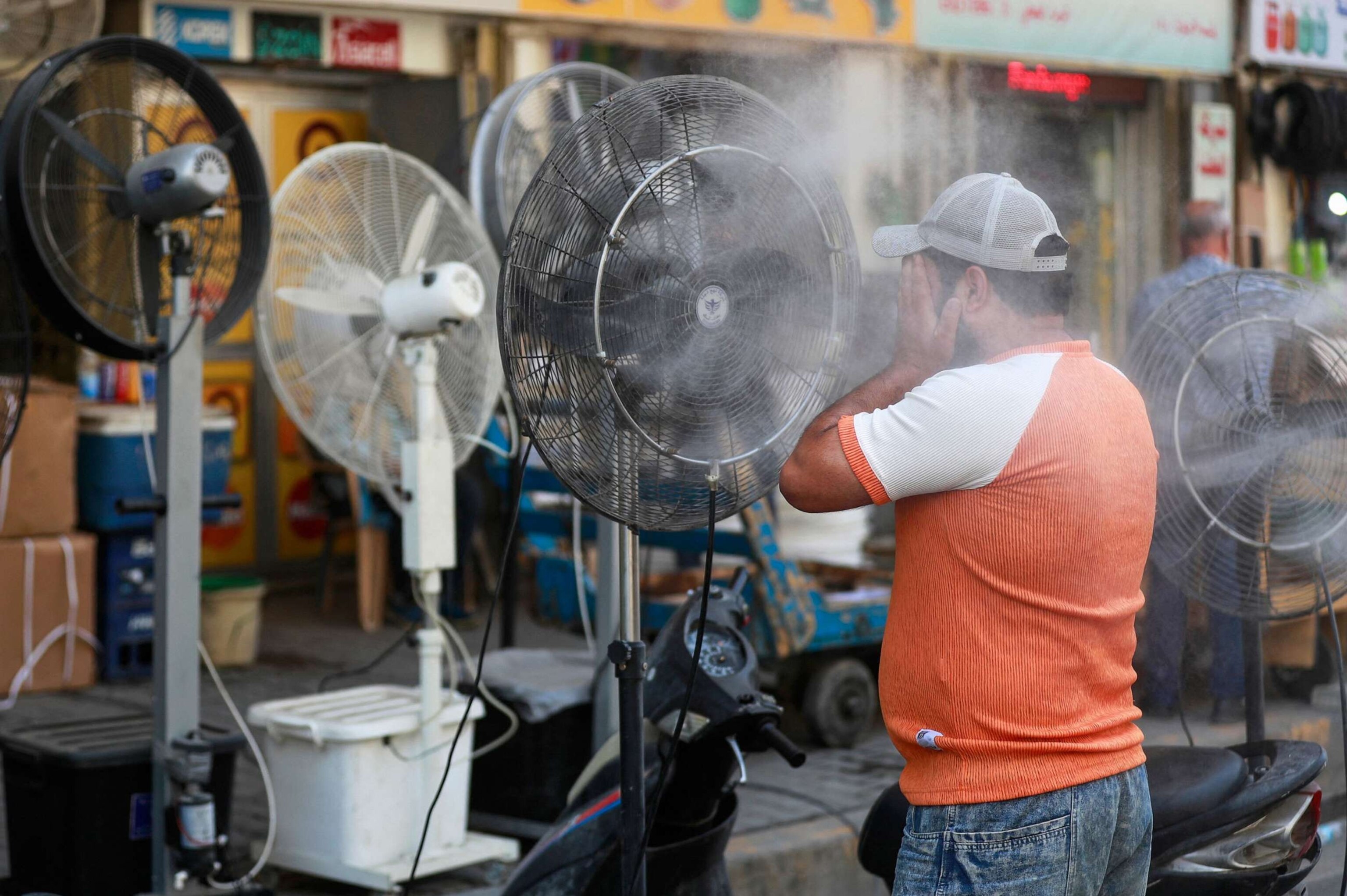 PHOTO: A man cools off at a mist dispenser set up on a street in central Baghdad amid soaring temperatures, July 23, 2023.