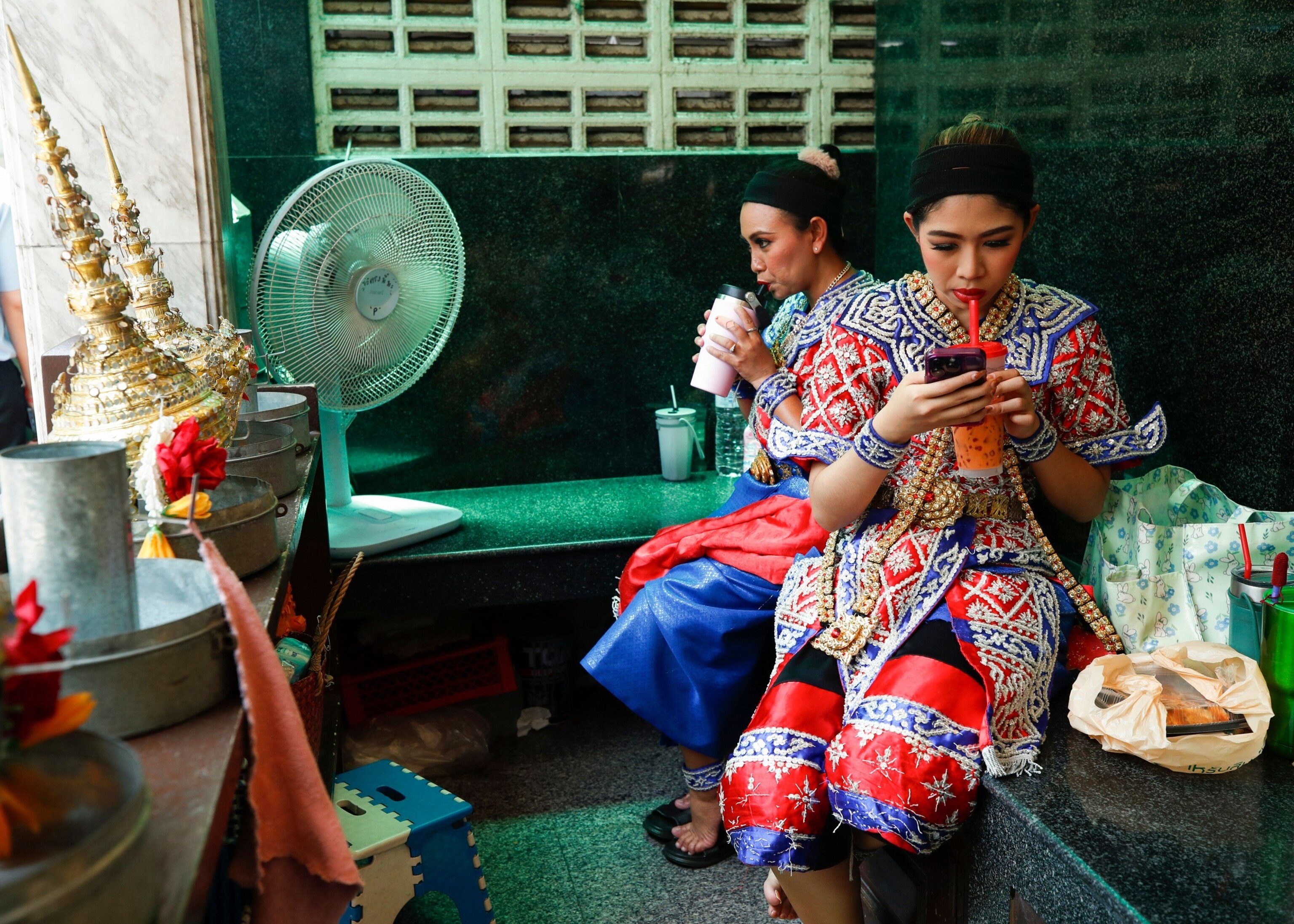 PHOTO: Thai dancers drink cold beverages and cool down from the heat with an electric fan as they take a break from a worshipping god performance, during a heatwave at the Erawan Shrine in Bangkok, Thailand, April 30, 2024.