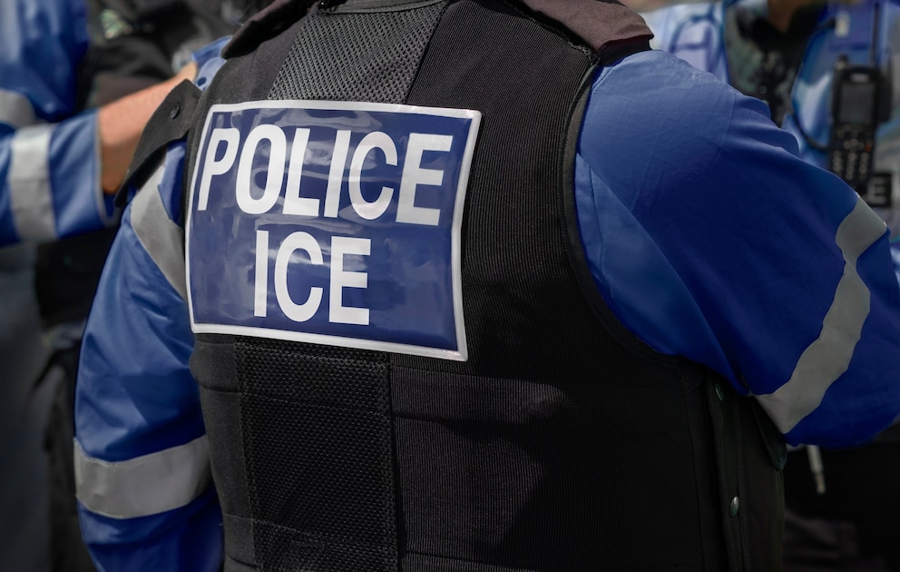PHOTO: Ice Police agents - Immigration and Customs Enforcement. Close-up of POLICE ICE marking on the back of worn by a trio of DHS police officers at the scene of an incident.