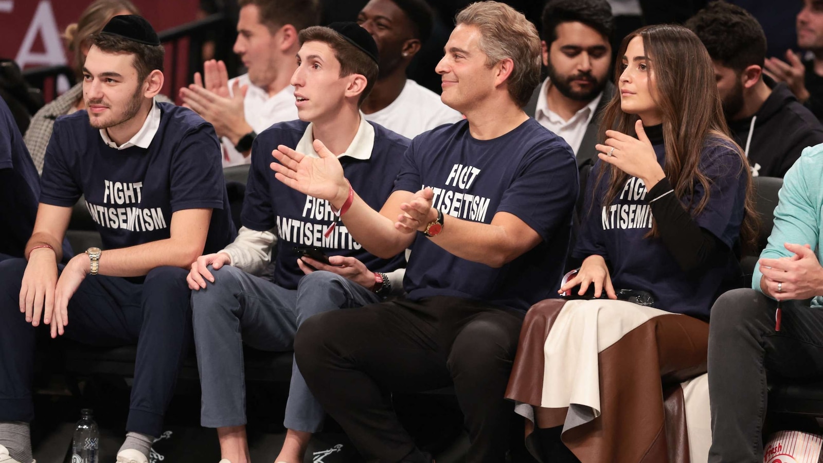 Fans wearing 'Fight Antisemitism' shirts sit courtside at Nets game