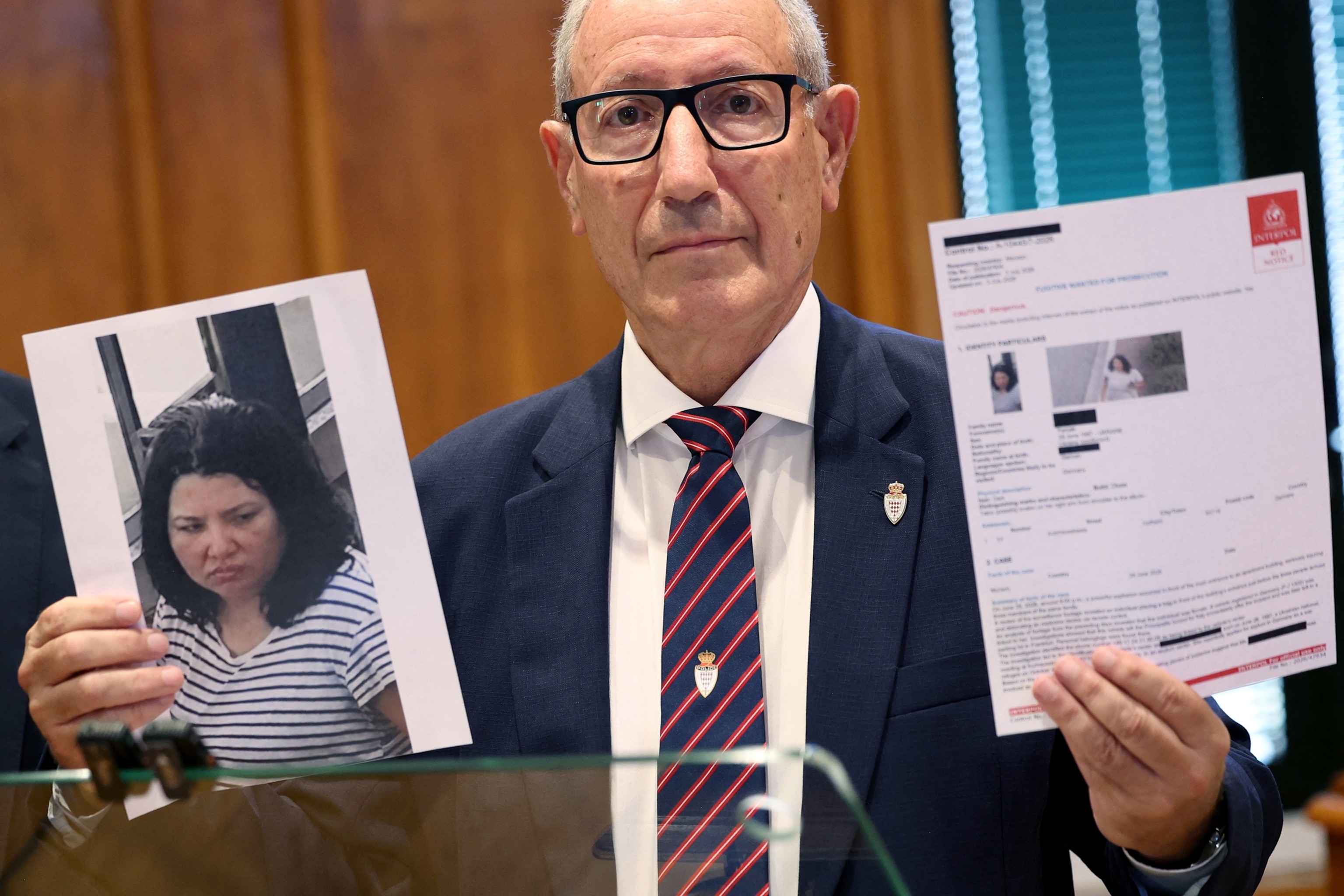 PHOTO: Monaco's Public Safety Director Eric Arella holds up the red notice issued by Interpol, July 3, 2026, against Anastasiia Berezovska, 39, the suspect in a bombing in Monaco that injured three people, including a Ukrainian-born tycoon.