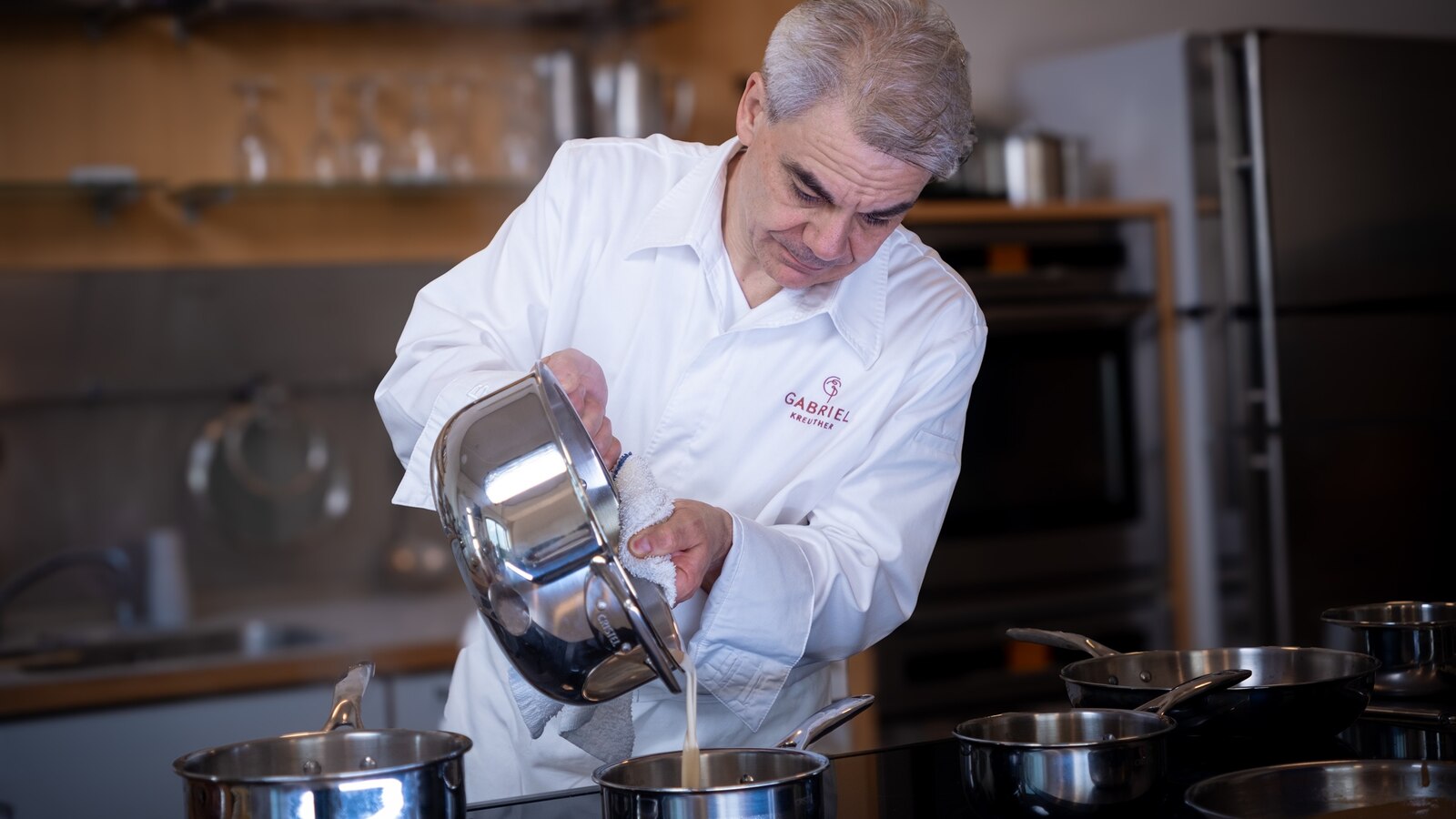 Chef Gabriel Kreuther pours sauce from the new Cristel cookware line. 