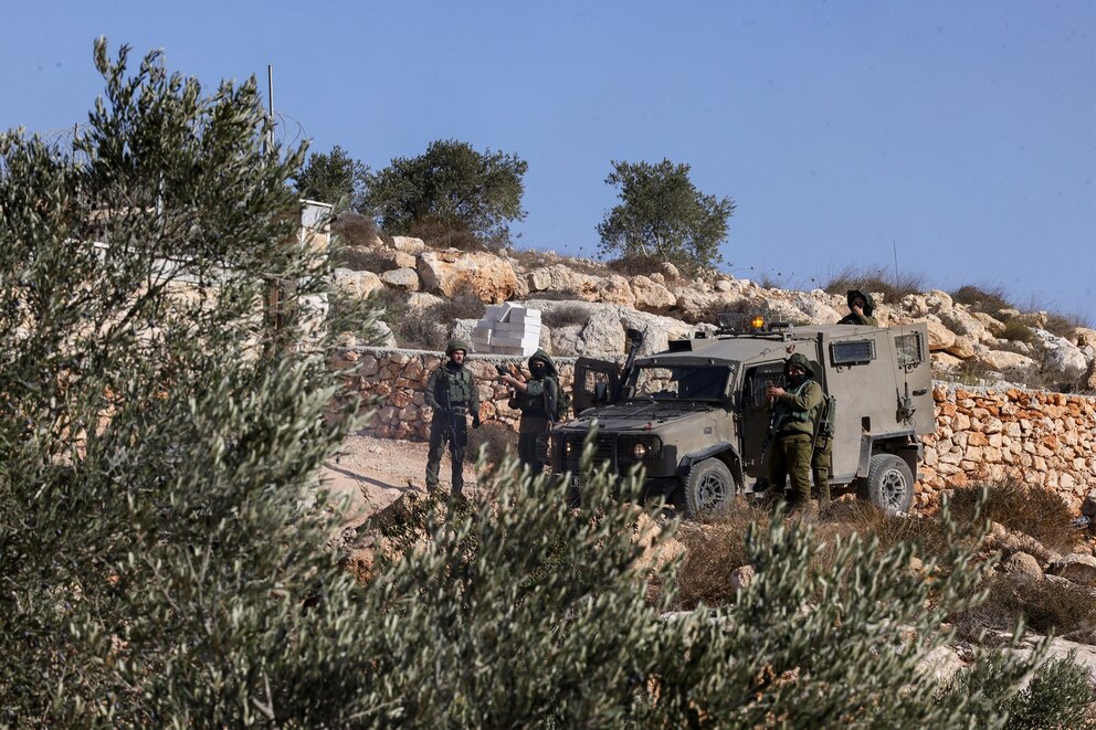 PHOTO: Israeli soldiers take positions near a car reportedly set alight by Israeli settlers attempting to disrupt them harvesting olives near the West Bank village of Turmos Ayya near Ramallah on Oct. 19, 2025