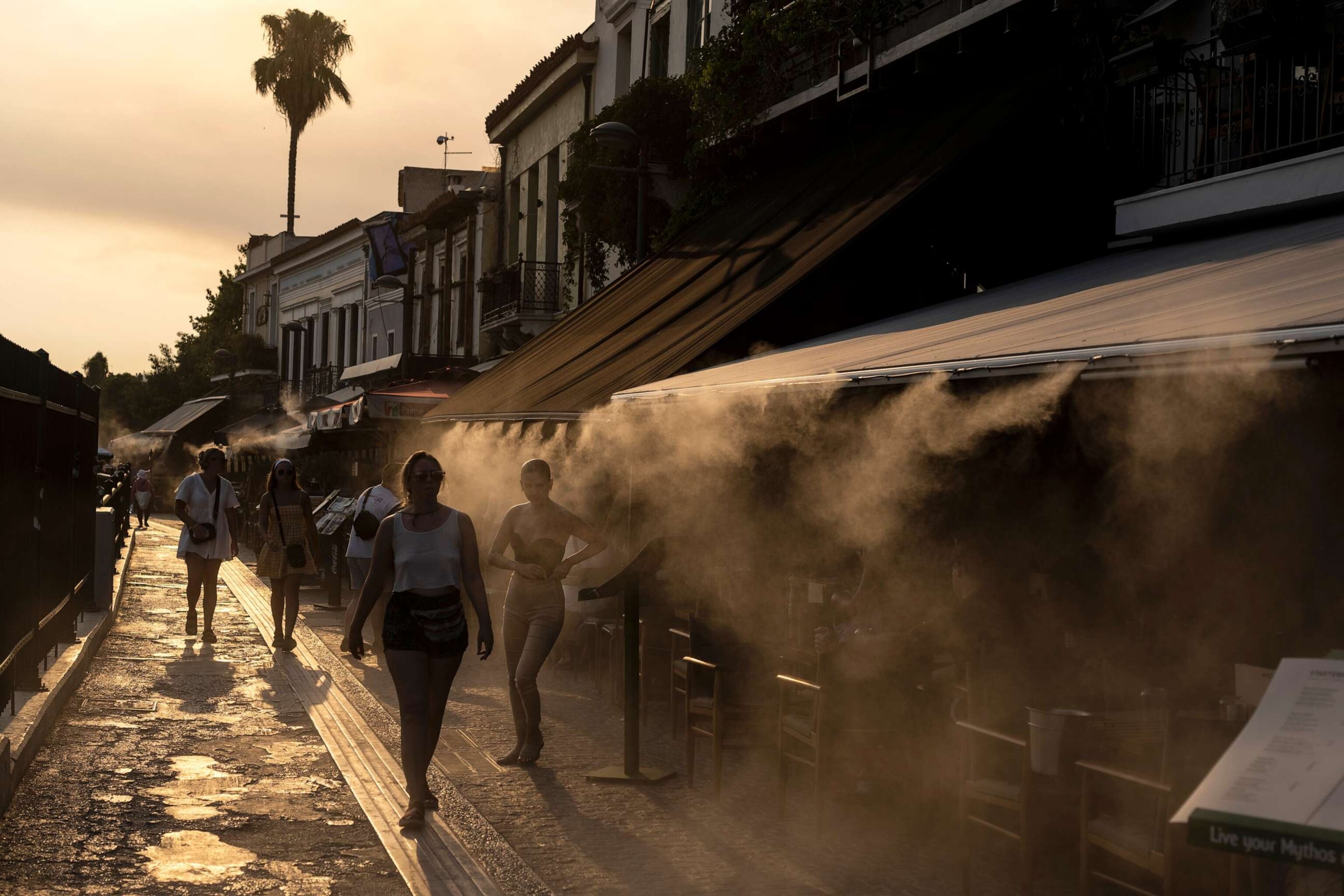 PHOTO: People walk next a mist machine to cool down, in Monastiraki district of Athens, July 20, 2023.