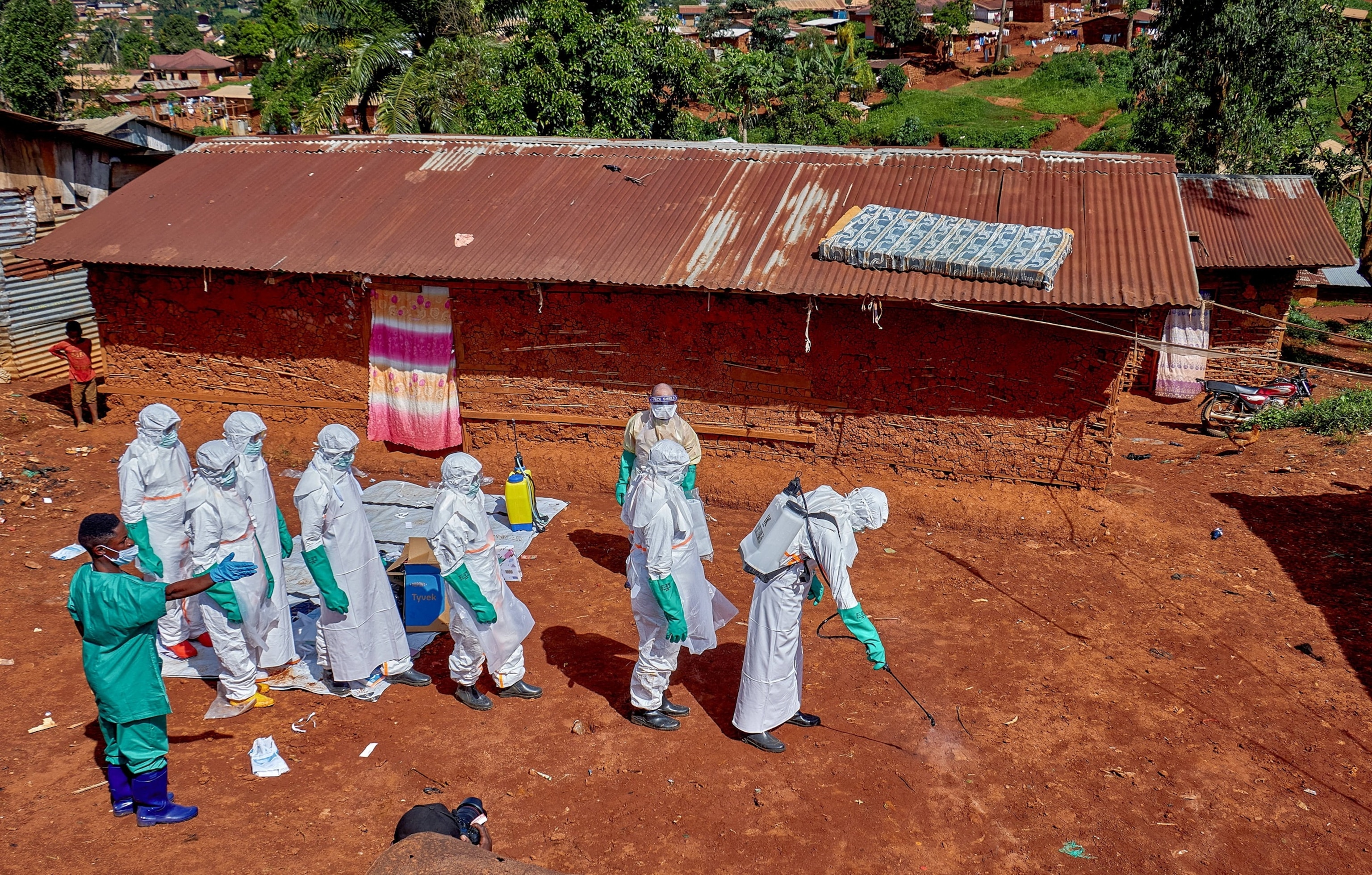 PHOTO: Red Cross workers wearing personal protective equipment  walk in a formation as they disinfect the ground outside the house of an unidentified man who died of Ebola in Mongbwalu, Democratic Republic of Congo, May 24, 2026.