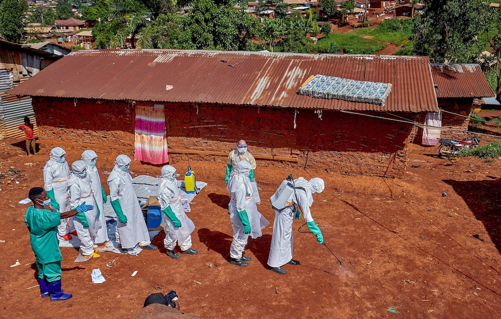 PHOTO: Red Cross workers wearing personal protective equipment walk in a formation as they disinfect the ground outside the house of an unidentified man who died of Ebola in Mongbwalu, Democratic Republic of Congo, May 24, 2026.