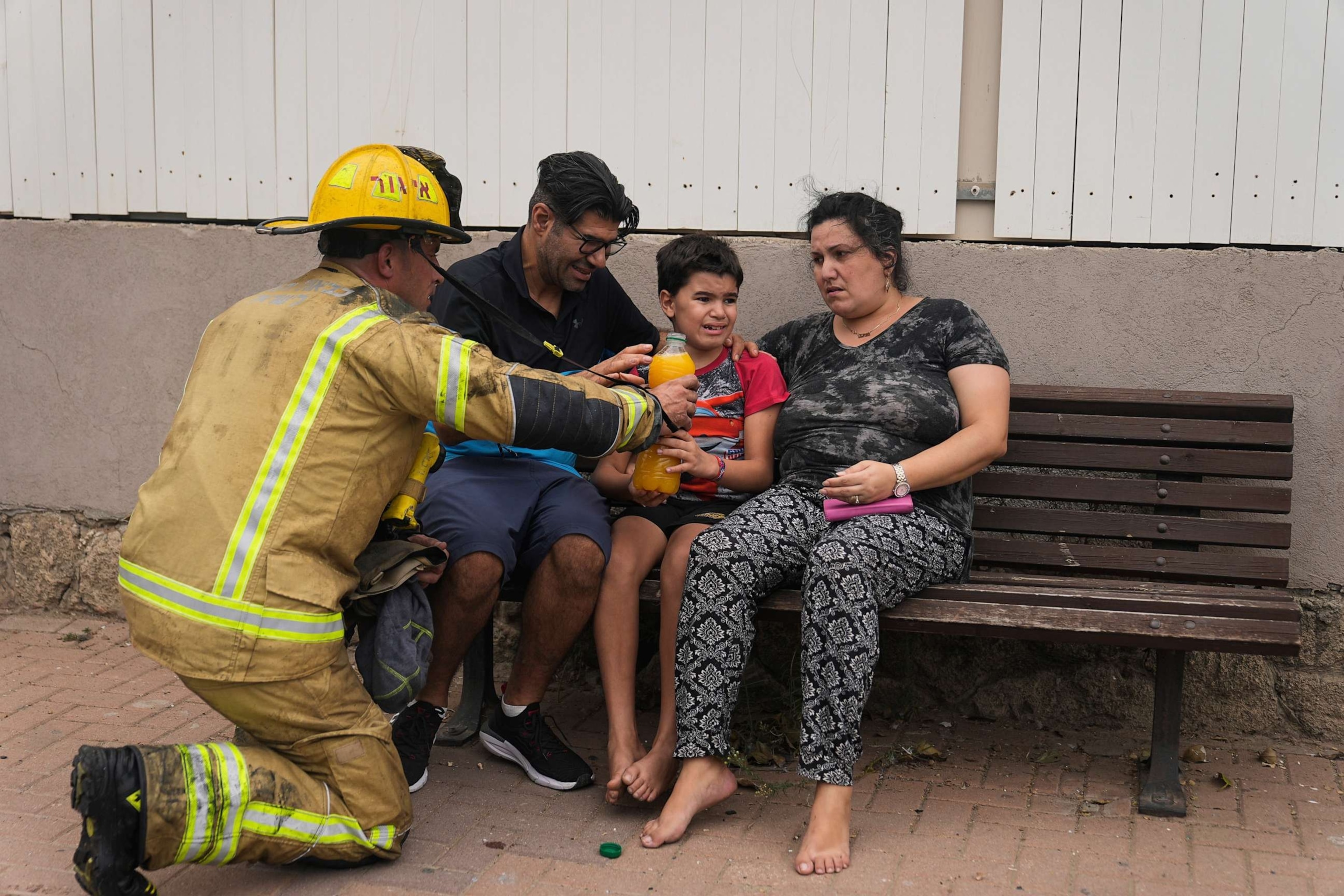 PHOTO: An Israeli firefighter hands a drink to a young child next to a site struck by a rocket fired from the Gaza Strip, in Ashkelon, southern Israel, Oct. 9, 2023.