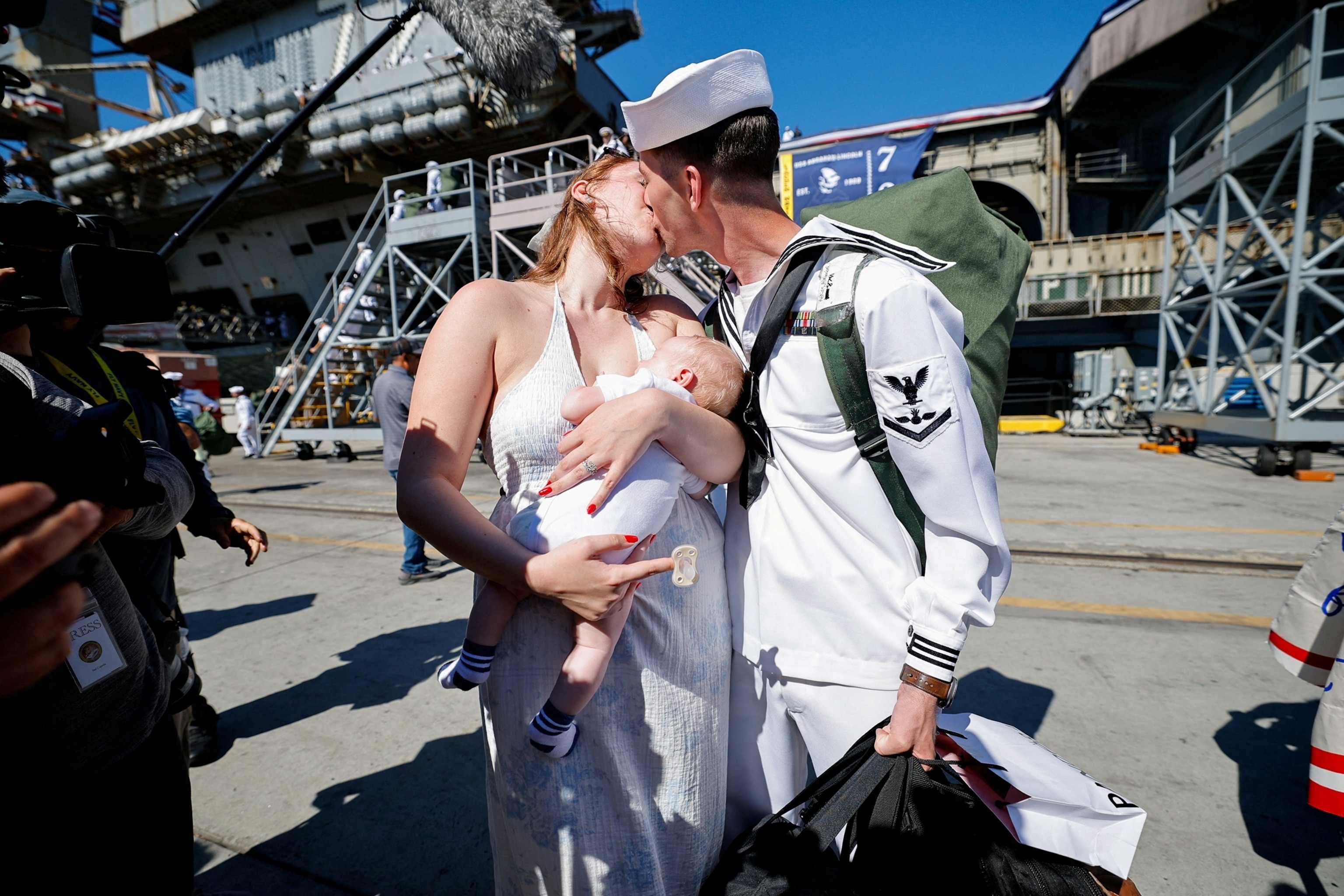 PHOTO: Saylor Caleb Atkins kisses his wife McKenzie Adkins, as she holds their baby after the US Navy Nimitz-class aircraft carrier USS Abraham Lincoln returned home in San Diego, Oct. 8, 2026.  