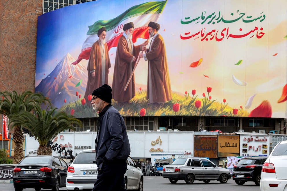 PHOTO: A man walks near a banner displayed at Valiasr Square in central Tehran on March 10, 2026, depicting Iran's late supreme leaders Ayatollah Ruhollah Khomeini and Ayatollah Ali Khamenei and new supreme leader Mojtaba Khamenei.