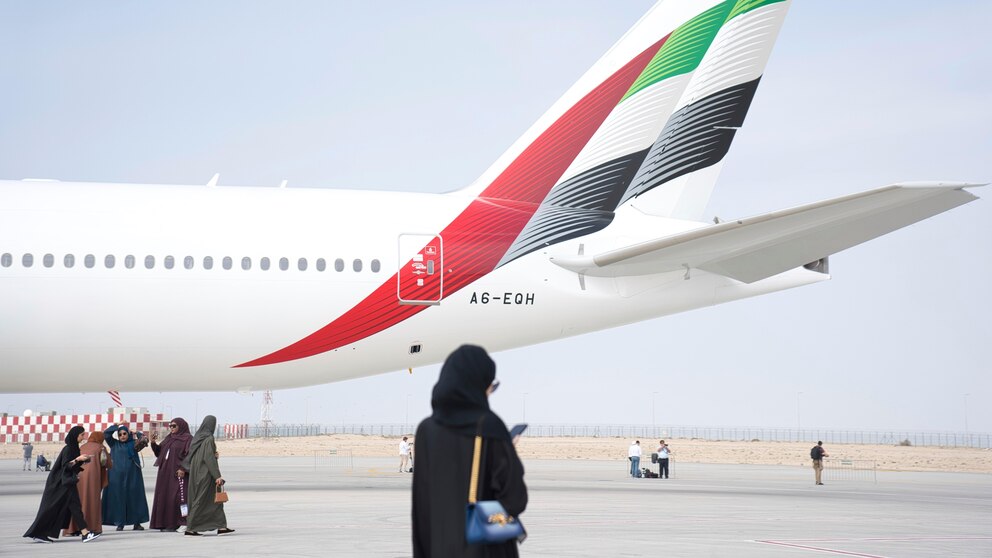 Emirati women walk past the tail of an Emirates Boeing 777 at the Dubai Air Show in Dubai, United Arab Emirates, Wednesday, Nov. 15, 2023. (AP Photo/Jon Gambrell)