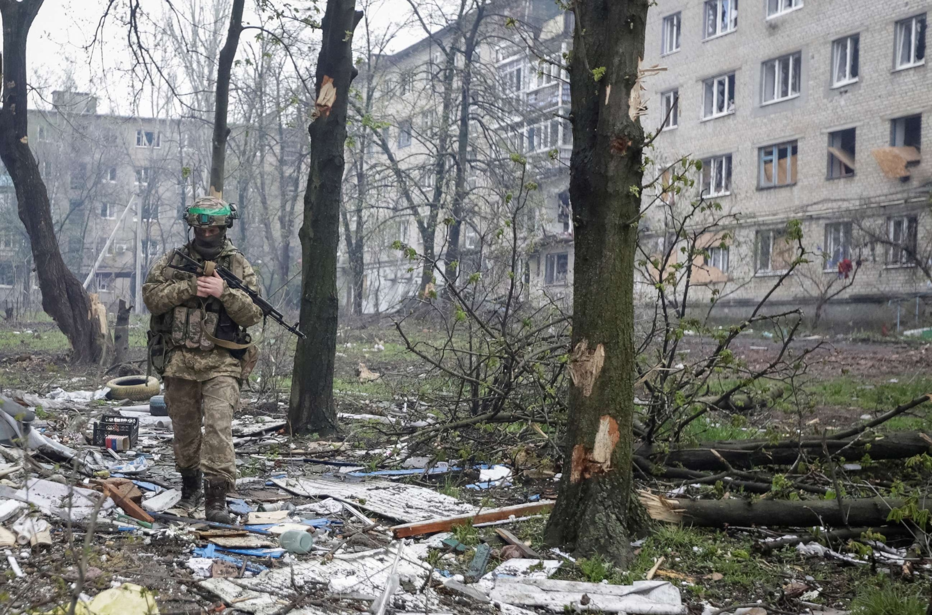 PHOTO: A Ukrainian service member walks near residential buildings damaged by a Russian military strike in the front line town of Bakhmut, in Donetsk region, Ukraine, April 21, 2023.