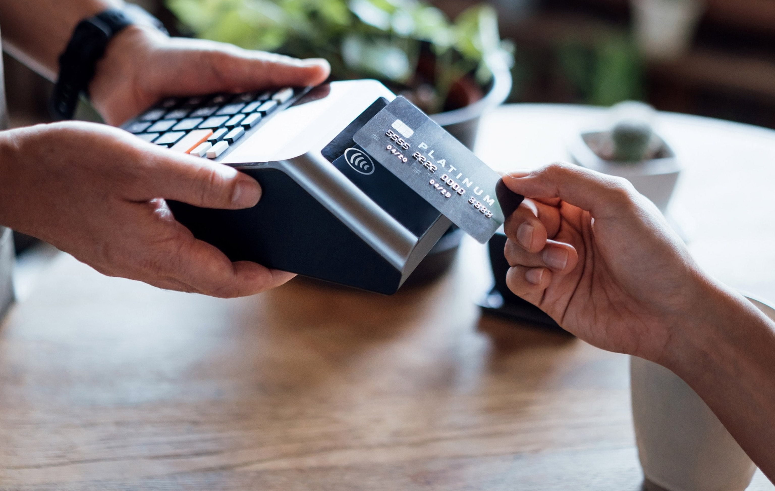 PHOTO: Close up of a woman's hand paying bill with credit card in a cafe, scanning on a card machine.