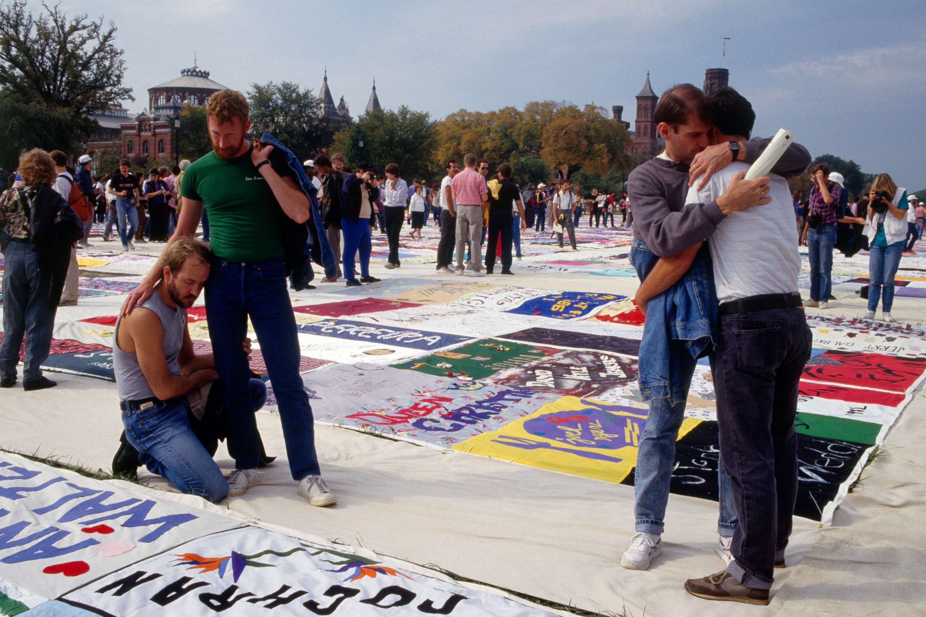 PHOTO: Demonstrators gather in homage of the victims of AIDS, represented by a large patchwork quilt.