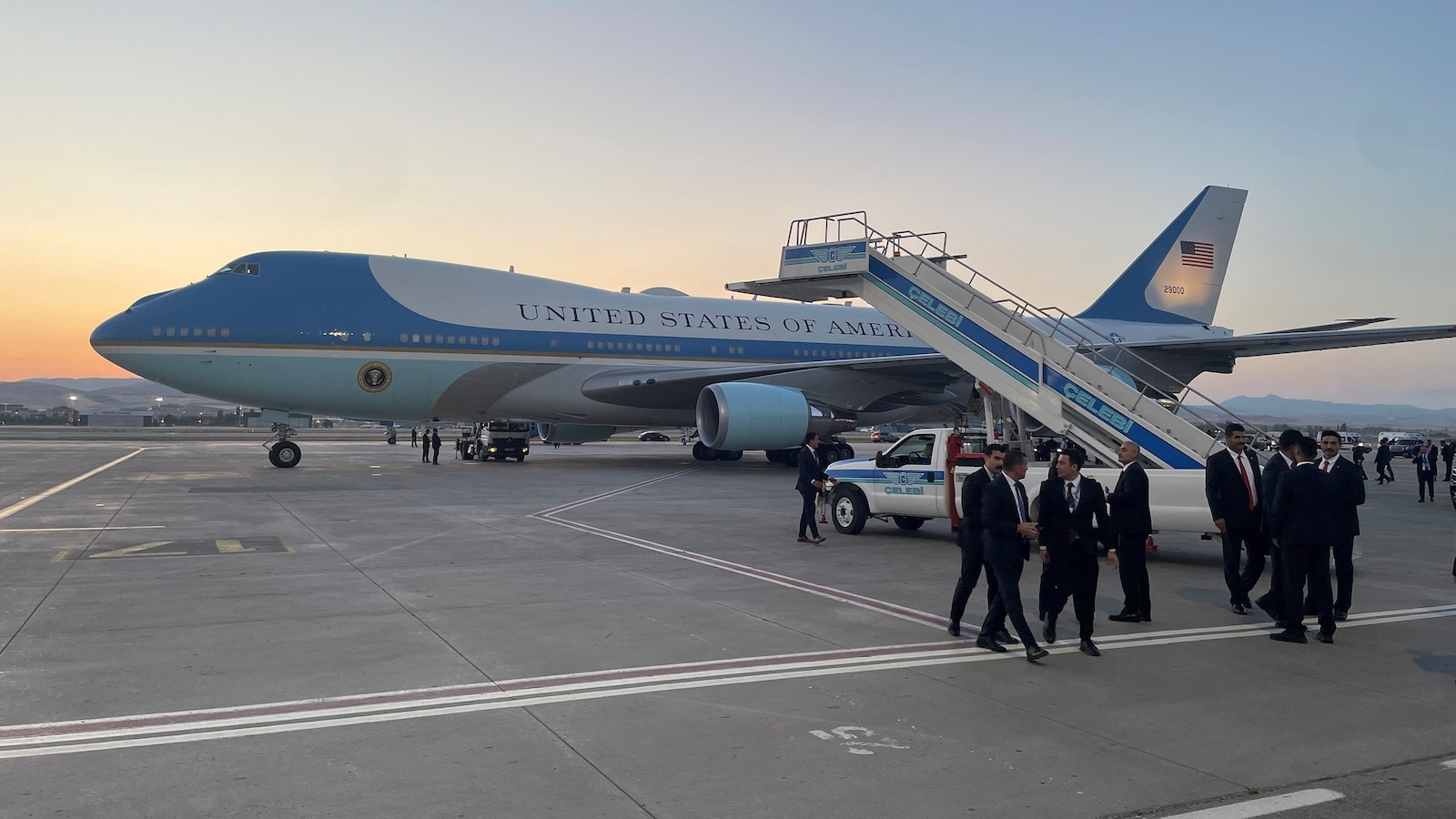 A United States Air Force aircraft parked on an airport tarmac with people nearby.