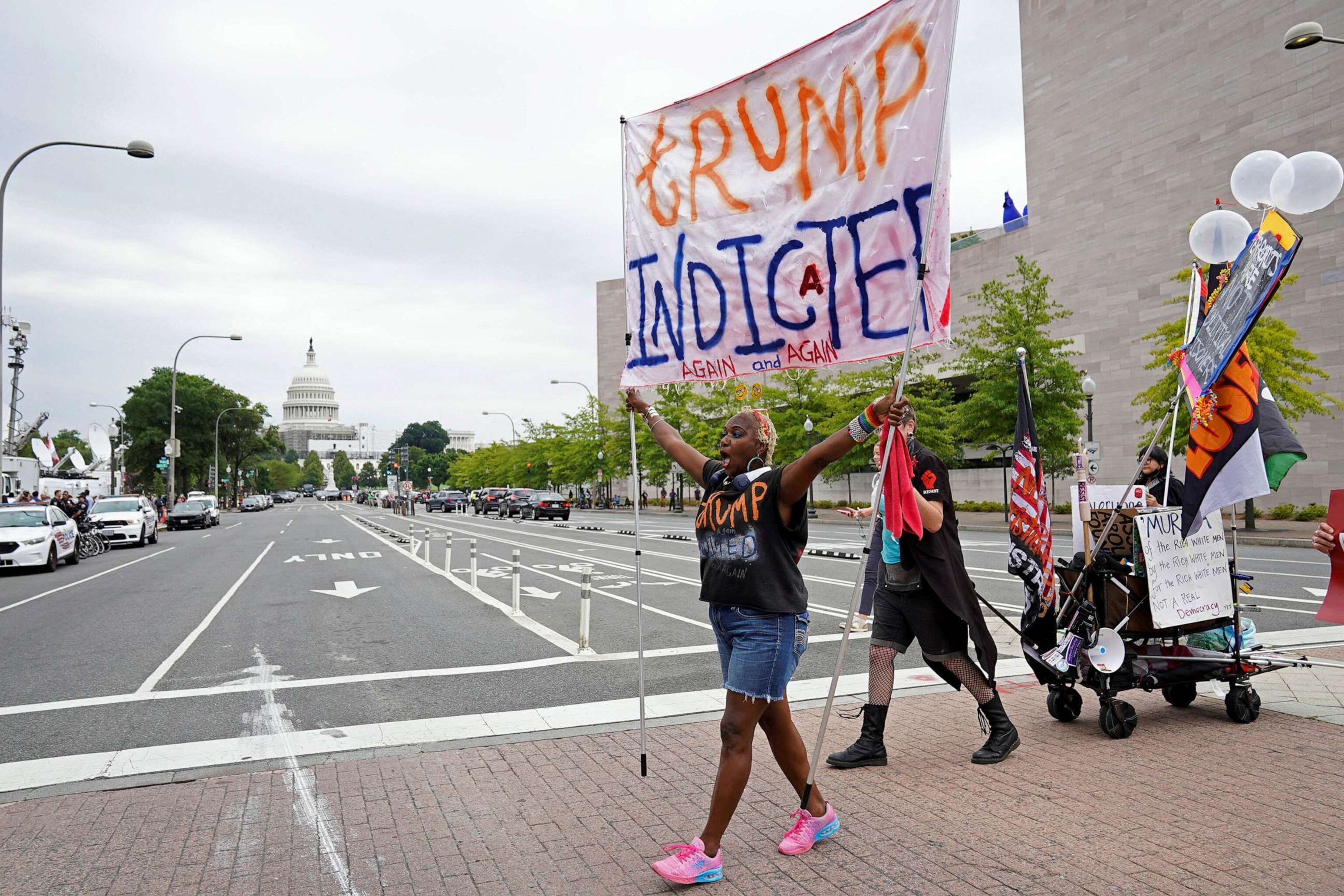 PHOTO: A demonstrator carries a banner, as people gather on the day former U.S. President Donald Trump, who is facing federal charges related to attempts to overturn his 2020 election defeat, appears at the U.S. District Court in Washington, Aug. 3, 2023.