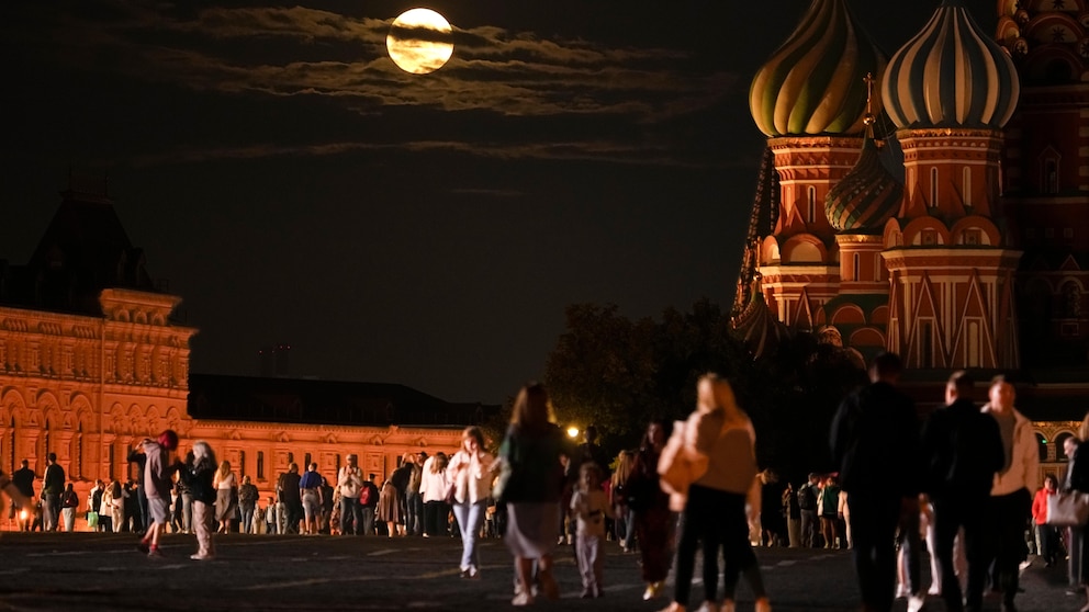 The August Super Blue Moon sets behind a historical building and the St. Basil's Cathedral, right, as people walk in Red Square in Moscow, Russia, Wednesday, Aug. 30, 2023. The cosmic curtain rises Wednesday night with the second full moon of the month, the reason it is considered blue. It is dubbed a supermoon because it is closer to Earth than usual, appearing especially big and bright. (AP Photo/Alexander Zemlianichenko)
