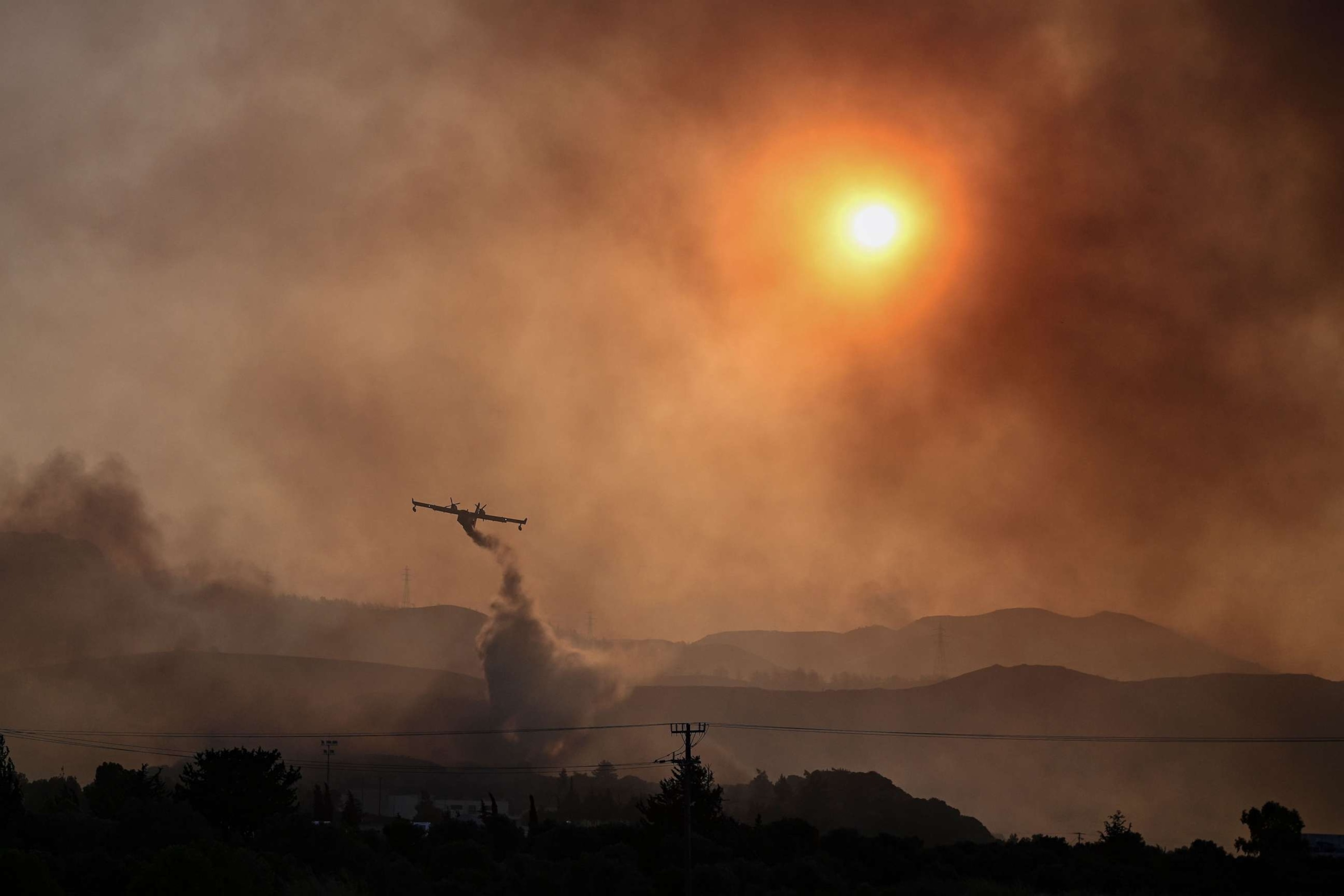 PHOTO: A Canadair firefighting airplane sprays water on a fire in Gennadi, on the southern part of the Greek island of Rhodes on July 25, 2023, on July 25, 2023, during a wildfire.