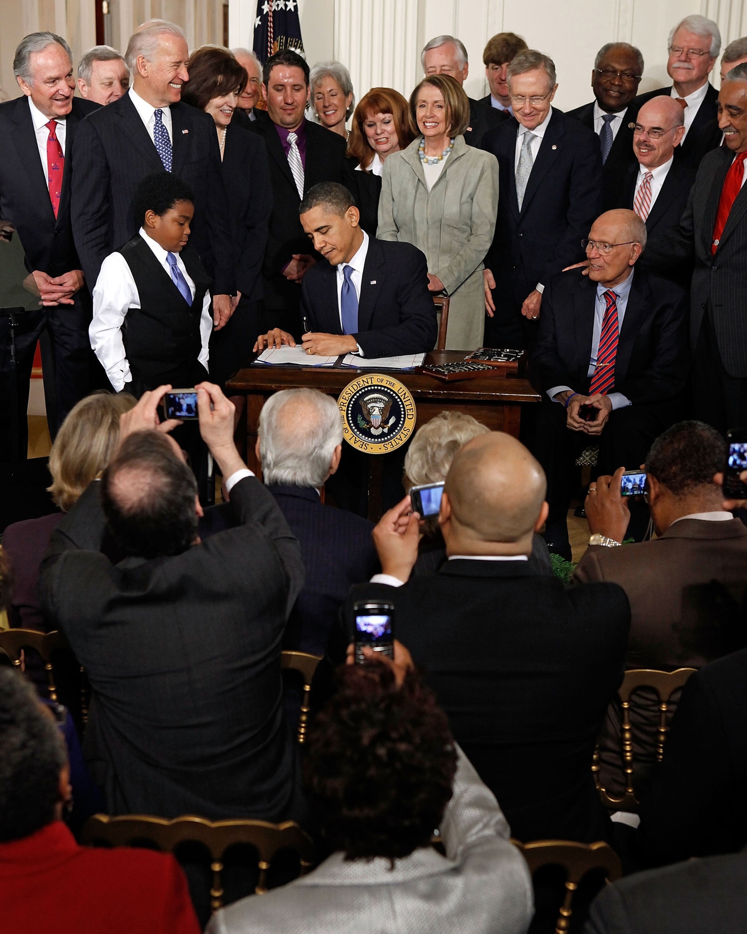 FOTO: El presidente Barack Obama firma la Ley de Atención Médica Asequible para Estados Unidos durante una ceremonia con sus compañeros demócratas en el Salón Este de la Casa Blanca el 23 de marzo de 2010 en Washington, DC.