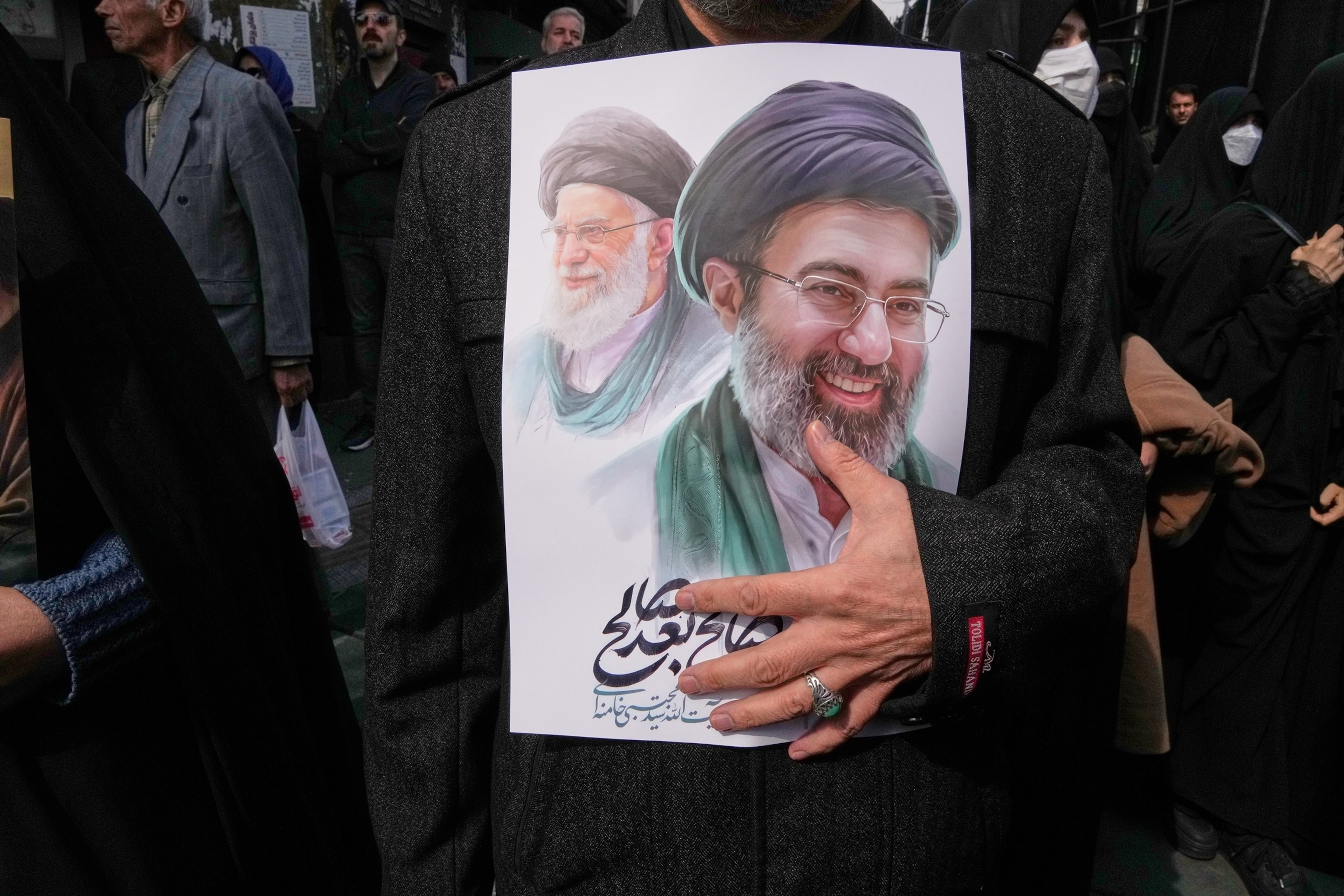 PHOTO: A mourner holds a poster depicting Ayatollah Mojtaba Khamenei, right, the successor to his late father Ayatollah Ali Khamenei, left, as supreme leader,  in Tehran, Iran, Wednesday, March 11, 2026.