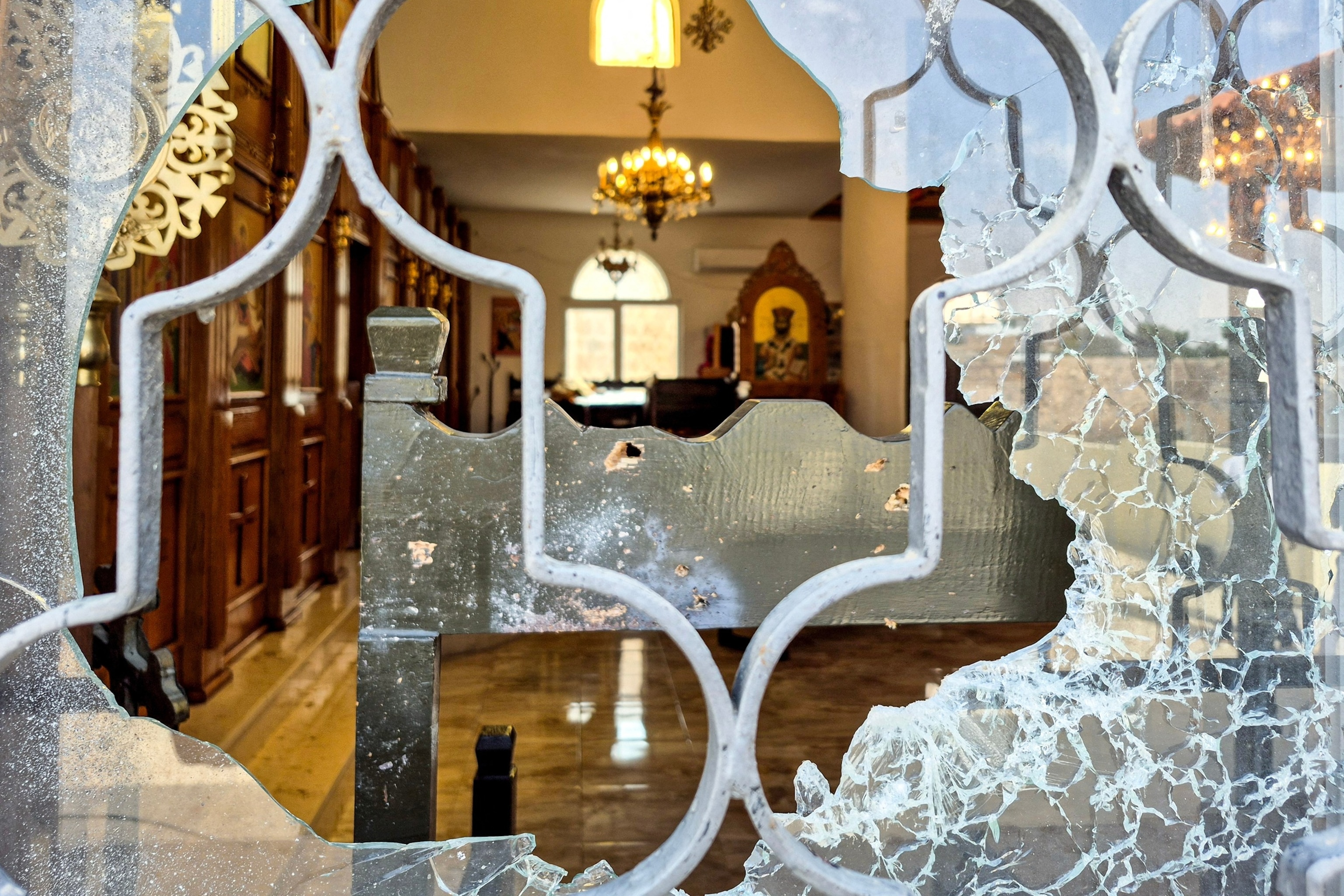 PHOTO: This picture taken through a smashed window shows bullet holes on a pew inside the Greek Orthodox church in the village of Hammoud in Karak governorate on Oct. 24, 2026,