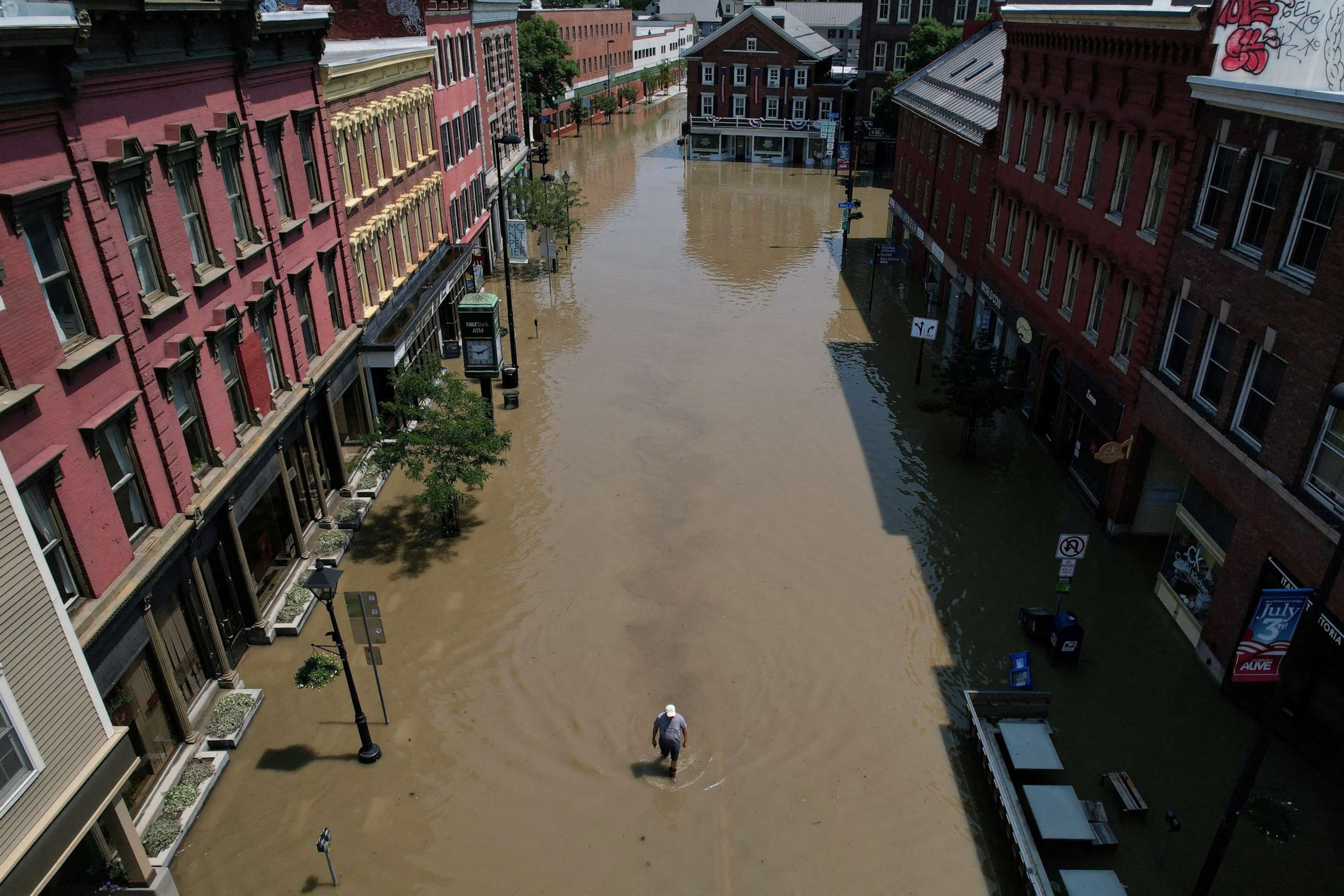 PHOTO: A man walks down a street flooded by recent rainstorms in Montpelier, Vermont, on July 11, 2023.