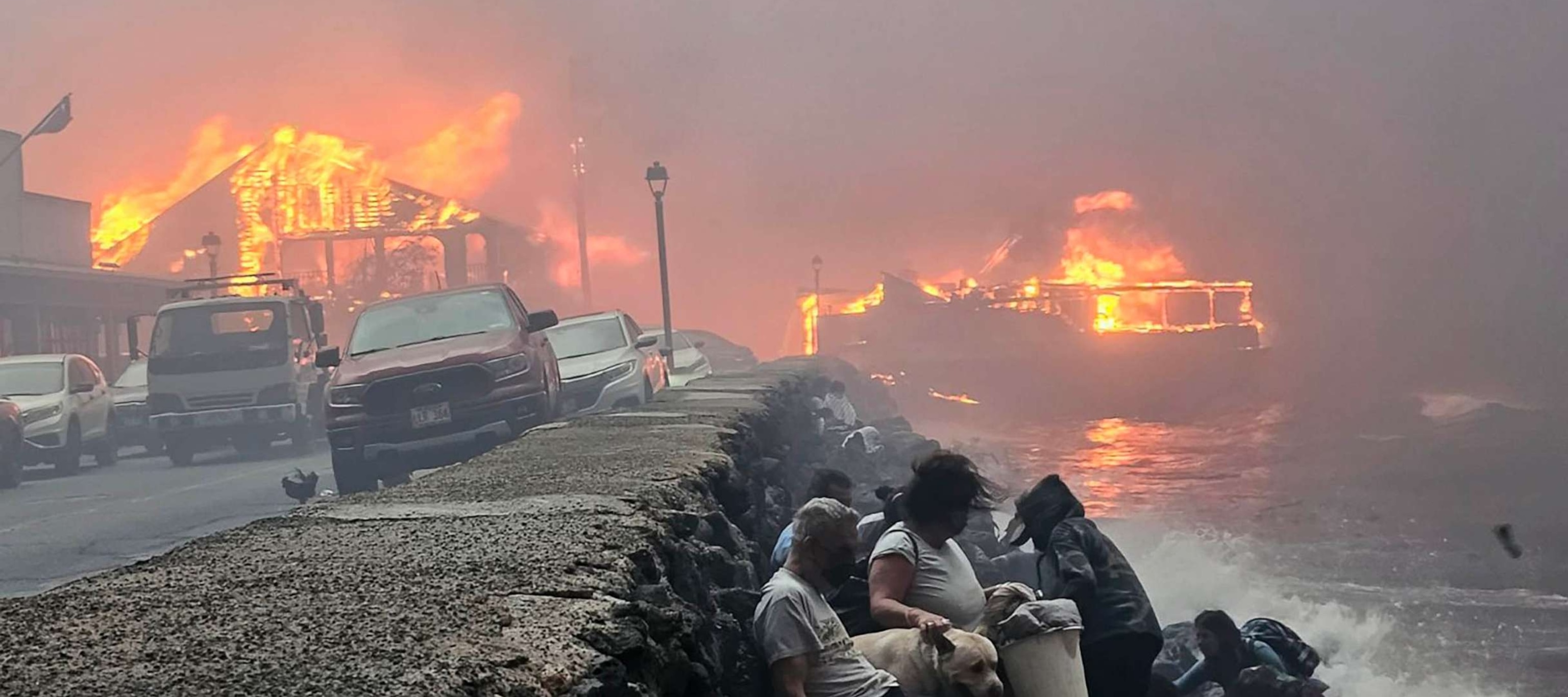 PHOTO: In this screen grab from a video, people sit on the shoreline to avoid the flames as a wildfire burns in Lahaina, Maui, Hawaii, on Aug. 8, 2023.