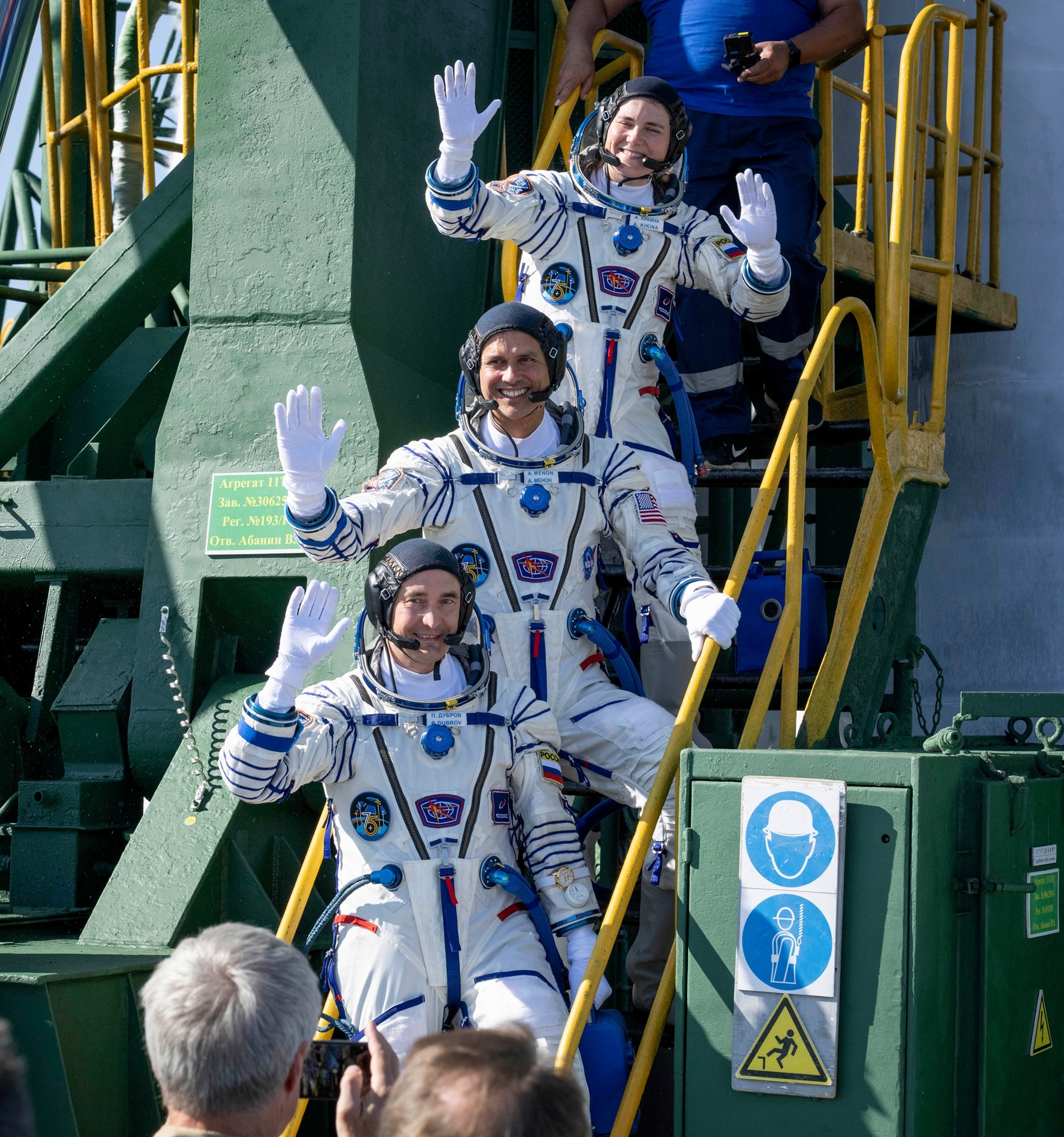 PHOTO: Cosmonaut Anna Kikina (top), NASA astronaut Anil Menon (C) and Roscosmos cosmonaut Pyotr Dubrov wave farewell prior to boarding the Soyuz MS-29 spacecraft for launch on July 14, 2026, at the Baikonur Cosmodrome in Baikonur, Kazakhstan. 