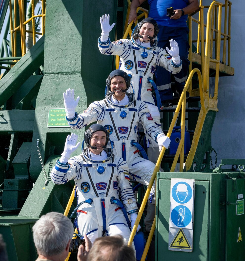 PHOTO: Cosmonaut Anna Kikina (top), NASA astronaut Anil Menon (C) and Roscosmos cosmonaut Pyotr Dubrov wave farewell prior to boarding the Soyuz MS-29 spacecraft for launch on July 14, 2026, at the Baikonur Cosmodrome in Baikonur, Kazakhstan.