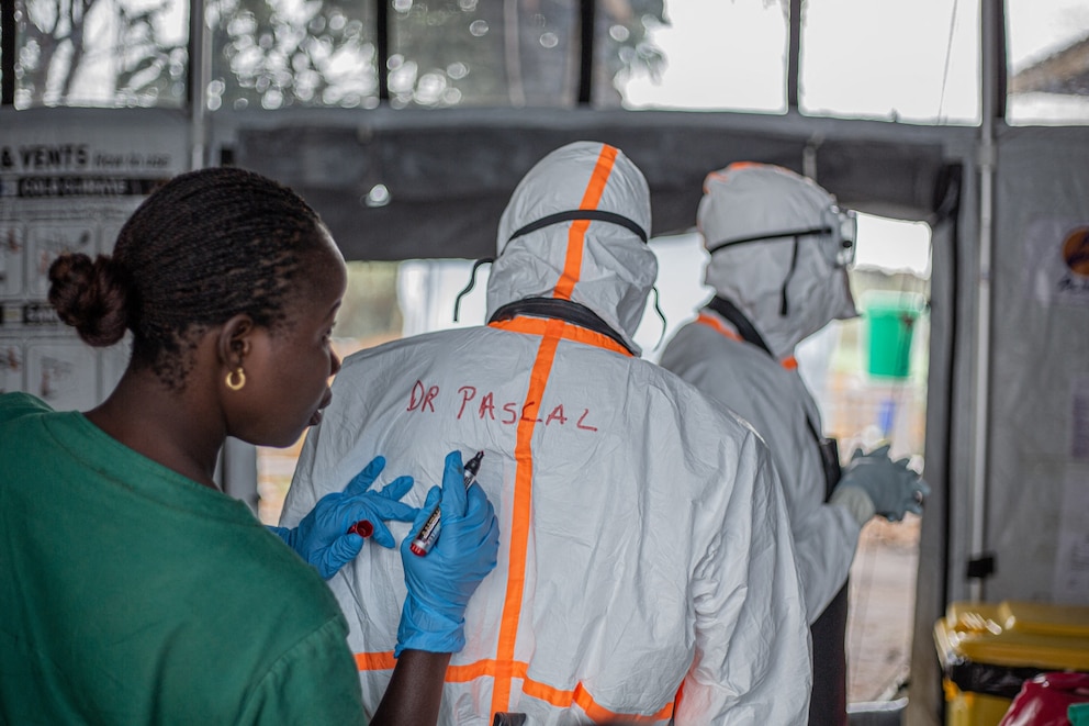 PHOTO: A worker writes a doctor's name on the back of his personal protective equipment suit before entering the Rwampara Ebola Treatment Centre to care for patients with Ebola virus disease in Bunia, Ituri, July 13, 2026.