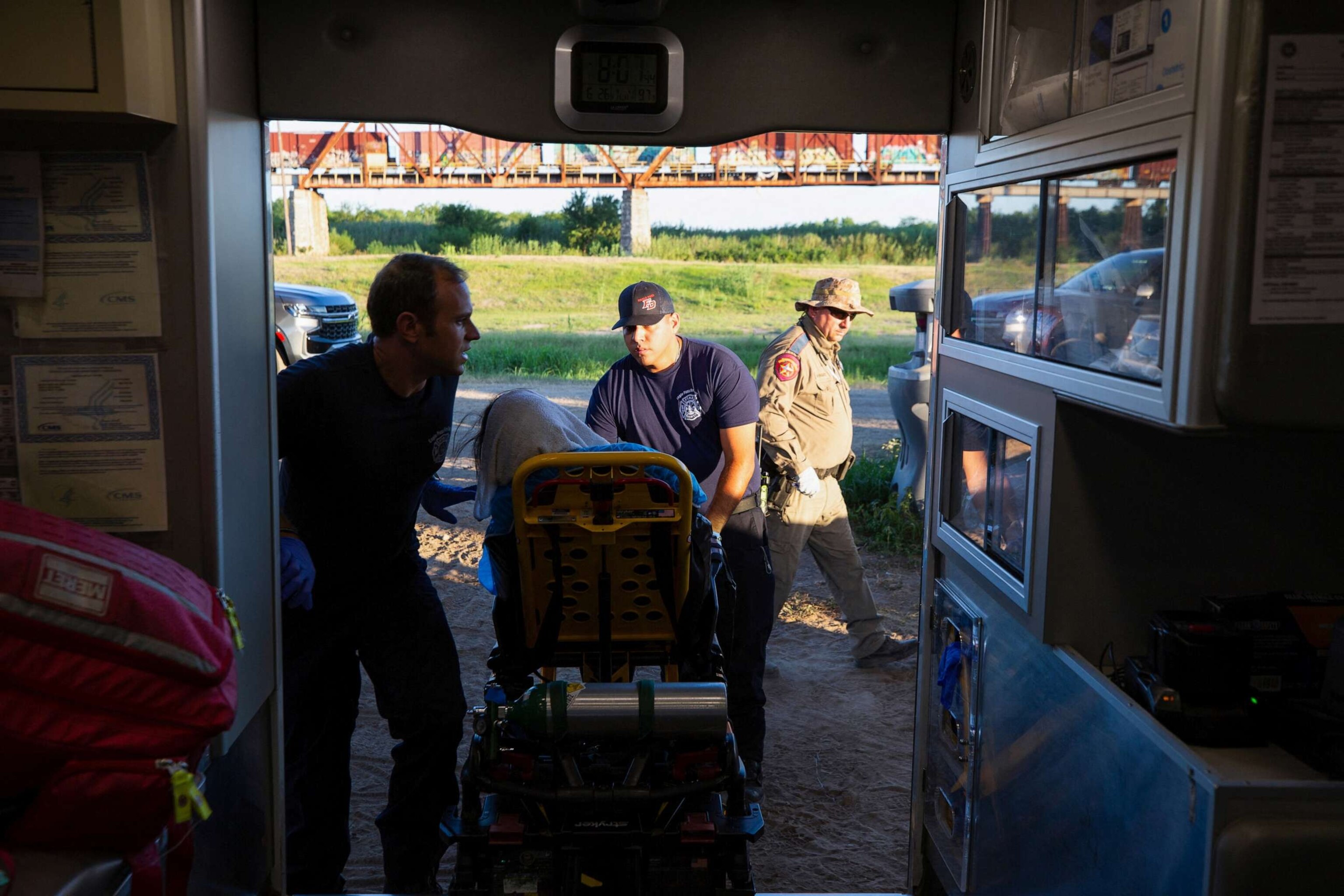 PHOTO: Firefighter EMT William Dorsey and firefighter EMT Rodrigo Pineda treat a migrant woman suffering from heat exhaustion in the border community of Eagle Pass, Texas, June 26, 2023.