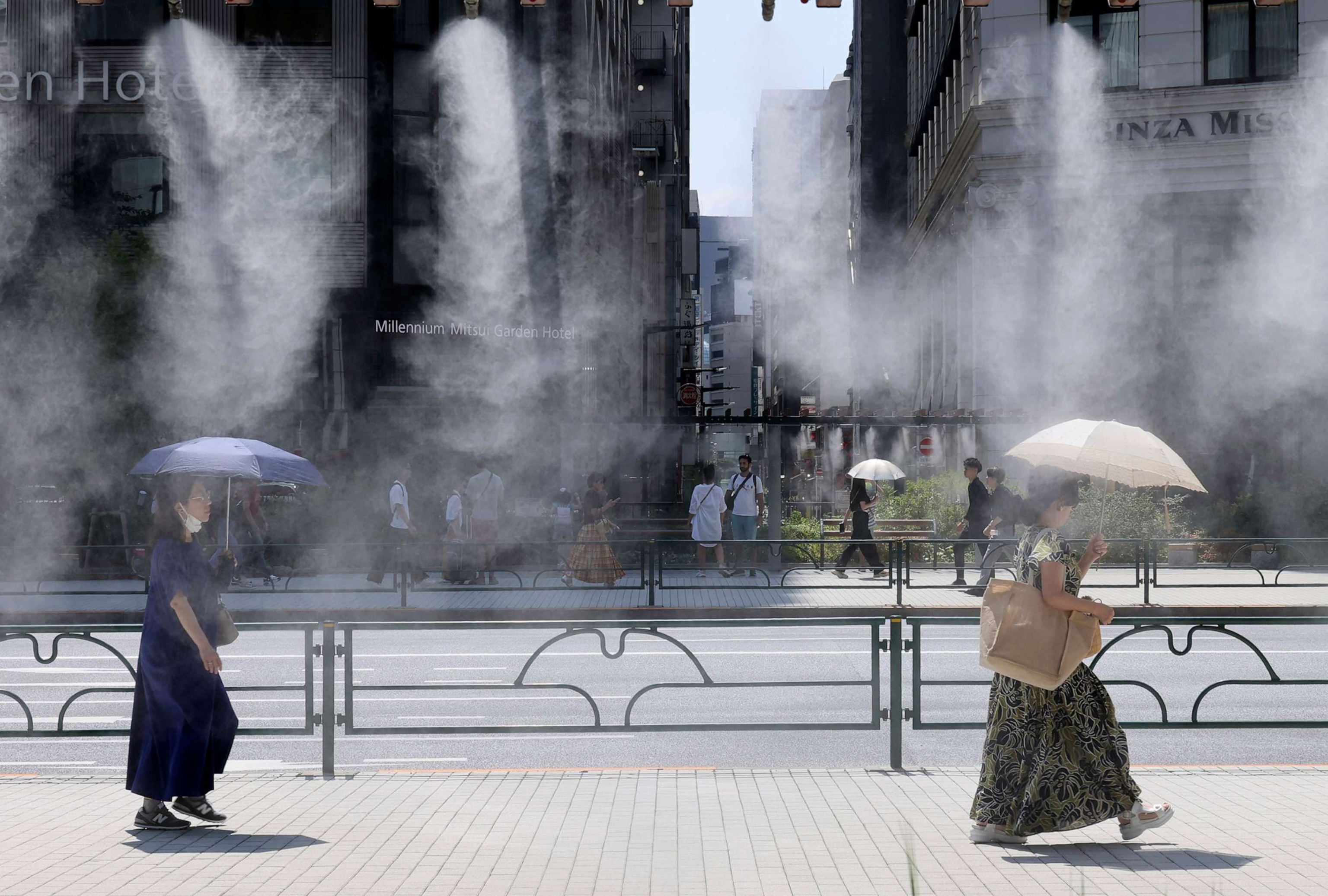 PHOTO: In this Aug. 19, 2023, file photo, people cool off under the artificial mist as the temperature rises in the Gonza district in Tokyo .