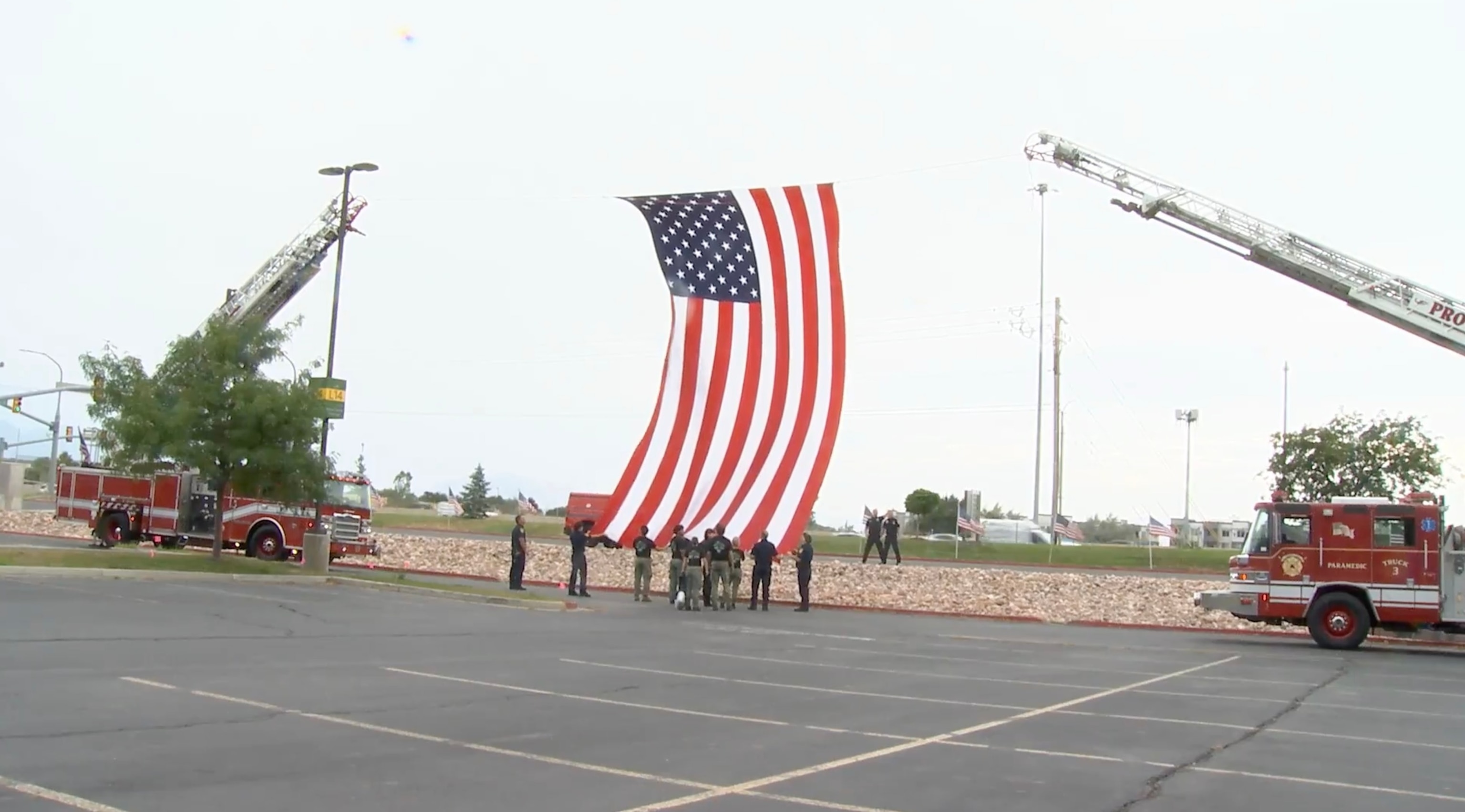 PHOTO: Utah firefighters raise a giant American flag between two ladder trucks ahead of a funeral procession, July 29, 2026,  for Provo Fire Capt. Spencer Long, his wife, Katrina, and their three sons, who were killed in a flash flood this month. 