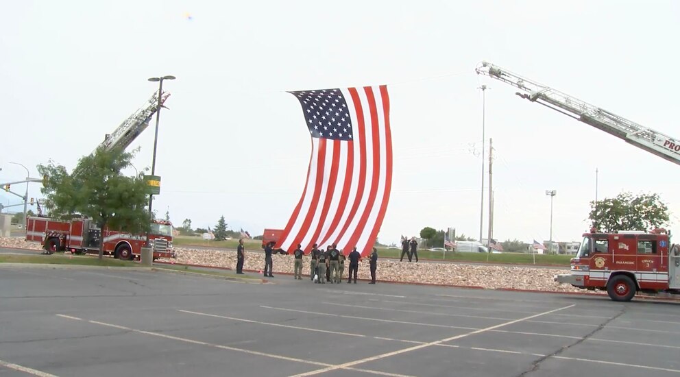 PHOTO: Utah firefighters raise a giant American flag between two ladder trucks ahead of a funeral procession, July 29, 2026, for Provo Fire Capt. Spencer Long, his wife, Katrina, and their three sons, who were killed in a flash flood this month.