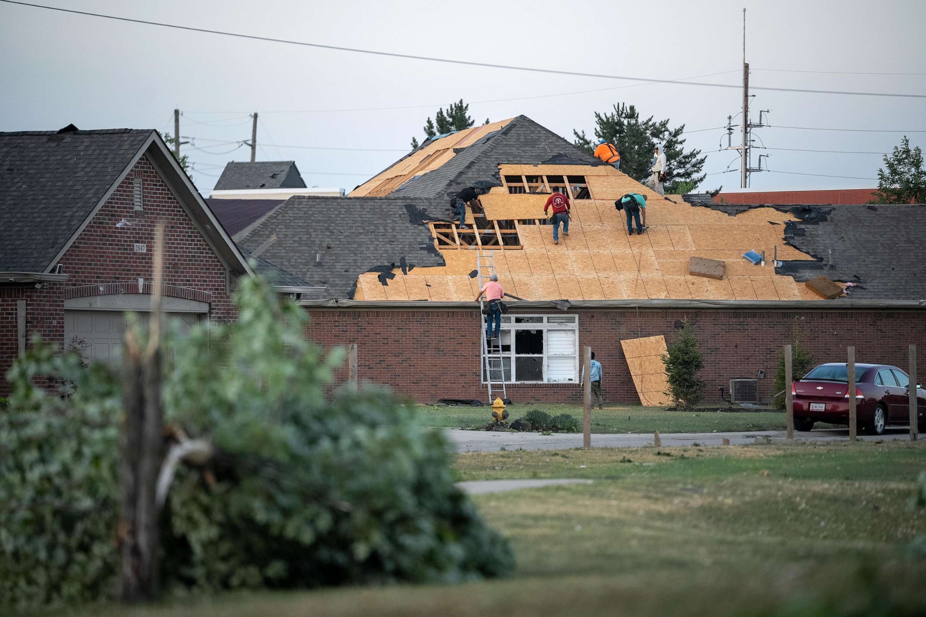 PHOTO: People work to repair damage done to a roof of building, June 25, 2023, after a tornado hit in Greenwood, Ind.