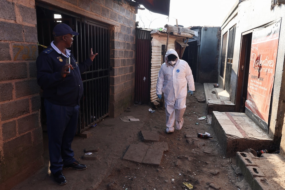 PHOTO: A Police oficer gestures next to a member of the forensics team after, according to the police, gunmen opened fire at an informal settlement in Cleveland, Johannesburg, South Africa, June 10, 2026.