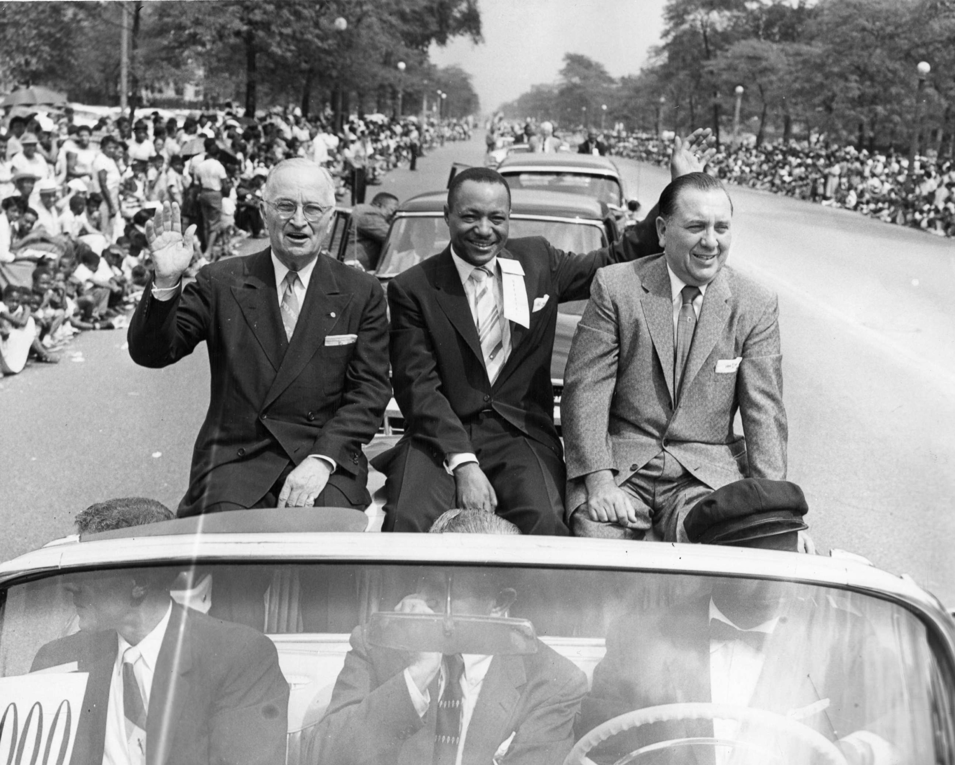 PHOTO: Former president Harry Truman, Chicago Defender publisher John H. Sengstacke, and Chicago mayor Richard J. Daley, wave to the crowd as they ride on a convertible at the Bud Billiken parade, in Chicago, in 1956. 