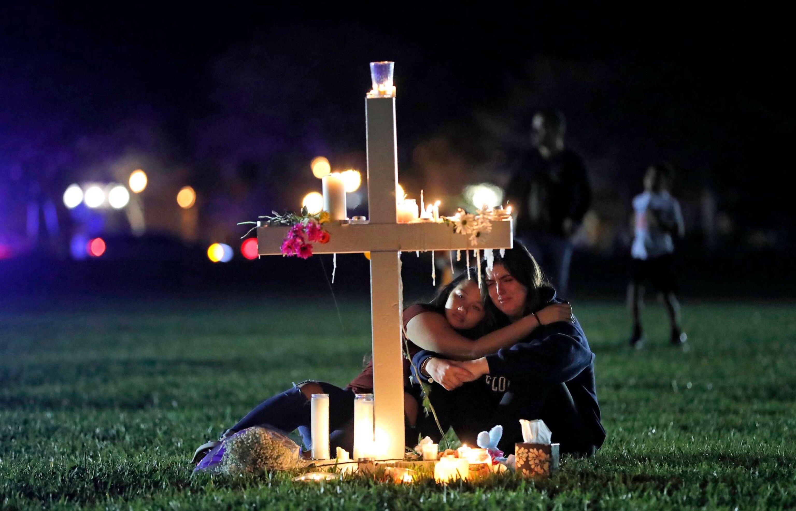 PHOTO: People comfort each other as they sit and mourn at one of seventeen crosses, Feb. 15, 2018, after a candlelight vigil for the victims of the shooting at Marjory Stoneman Douglas High School, in Parkland, Fla.