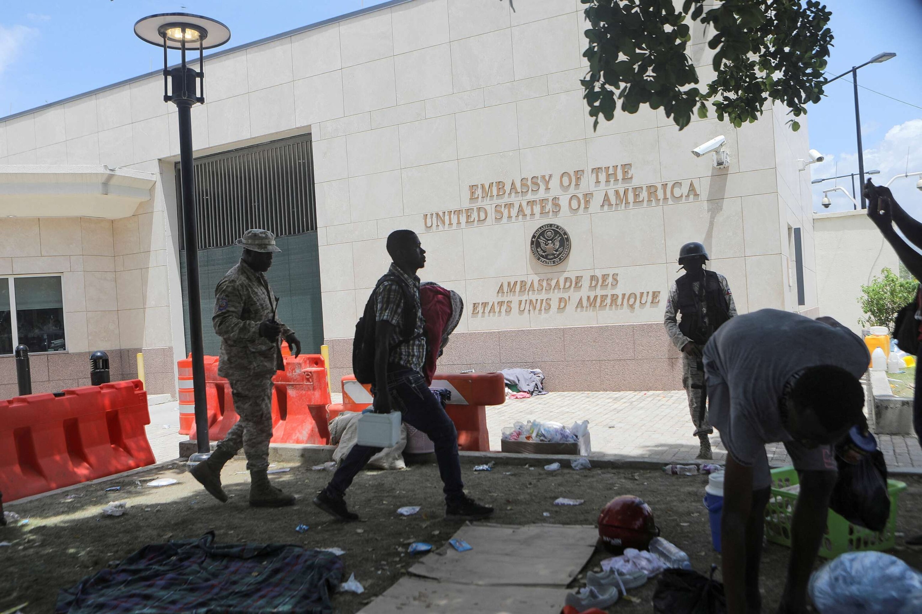 PHOTO: A man carries his belongings after officers of the Haitian National Police fired tear gas to clear a camp of people escaping the threat of armed gangs, in front of the U.S. Embassy, in Port-au-Prince, Haiti, on July 25, 2023.