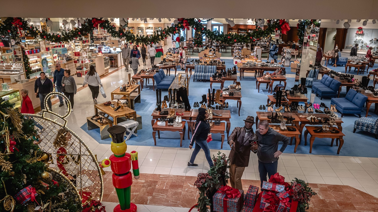 Shoppers pass near a Christmas tree display at the Von Maur store at the Oxmoor Mall on December 22, 2023 in Louisville, Kentucky.