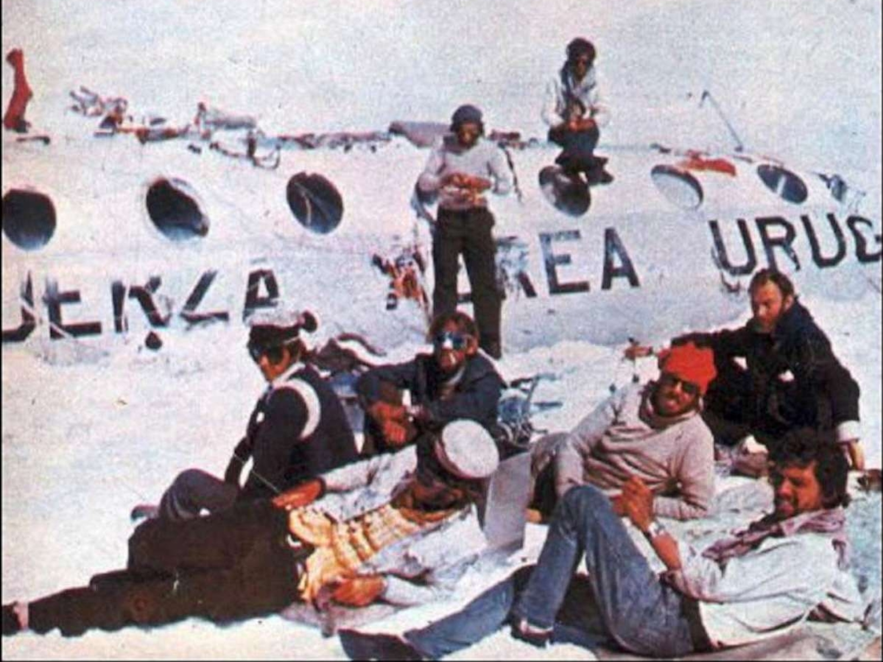 PHOTO: Pancho Delgado (sitting on the fuselage roof) and Roberto Canessa (standing to the right of Pancho) work on stitching together the sleeping bag that the expeditionaries will take on their trek to safety.