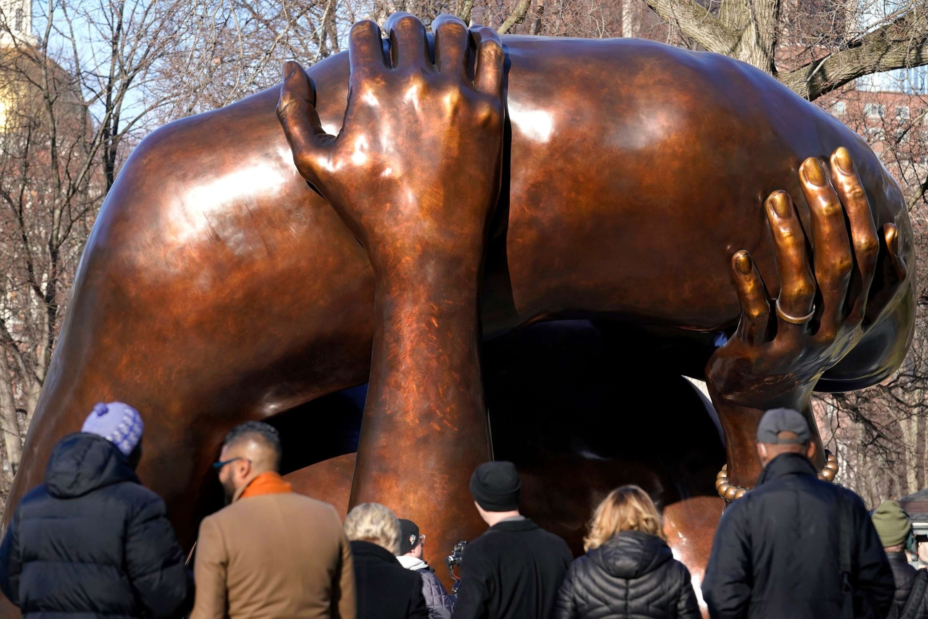 PHOTO: People stand near the 20-foot-high bronze sculpture "The Embrace," a memorial to Dr. Martin Luther King Jr. and Coretta Scott King, in the Boston Common, Tuesday, Jan. 10, 2023, in Boston.