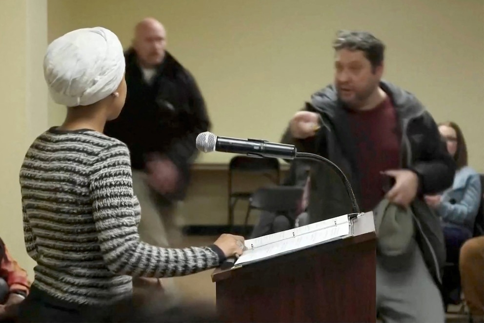 PHOTO: A man shouts at U.S. Rep. Ilhan Omar after spraying her, during a town hall meeting in Minneapolis