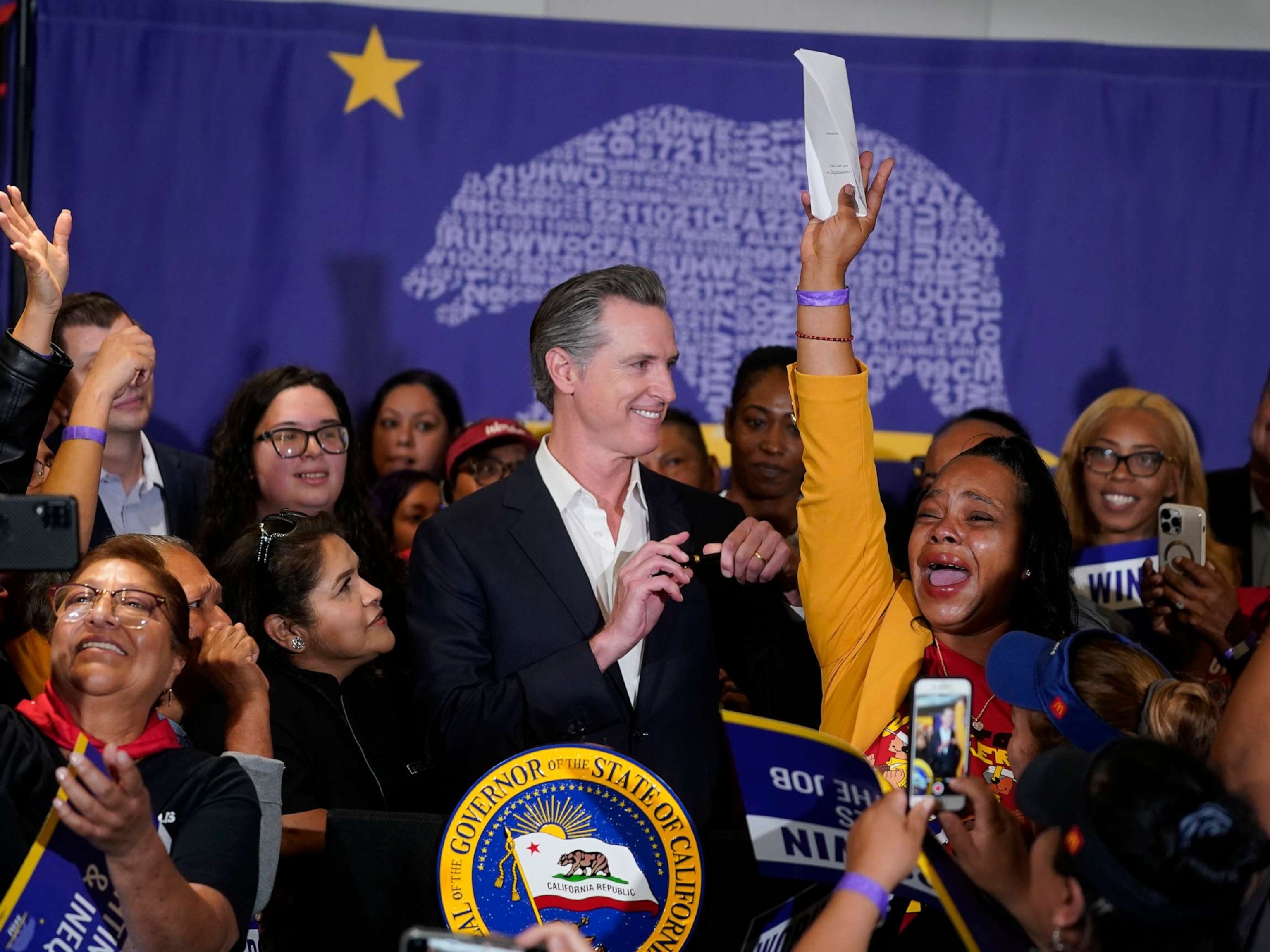 PHOTO: California Gov. Gavin Newsom signs the fast food bill surrounded by fast food workers at the SEIU Local 721 in Los Angeles on Sept. 28, 2023.