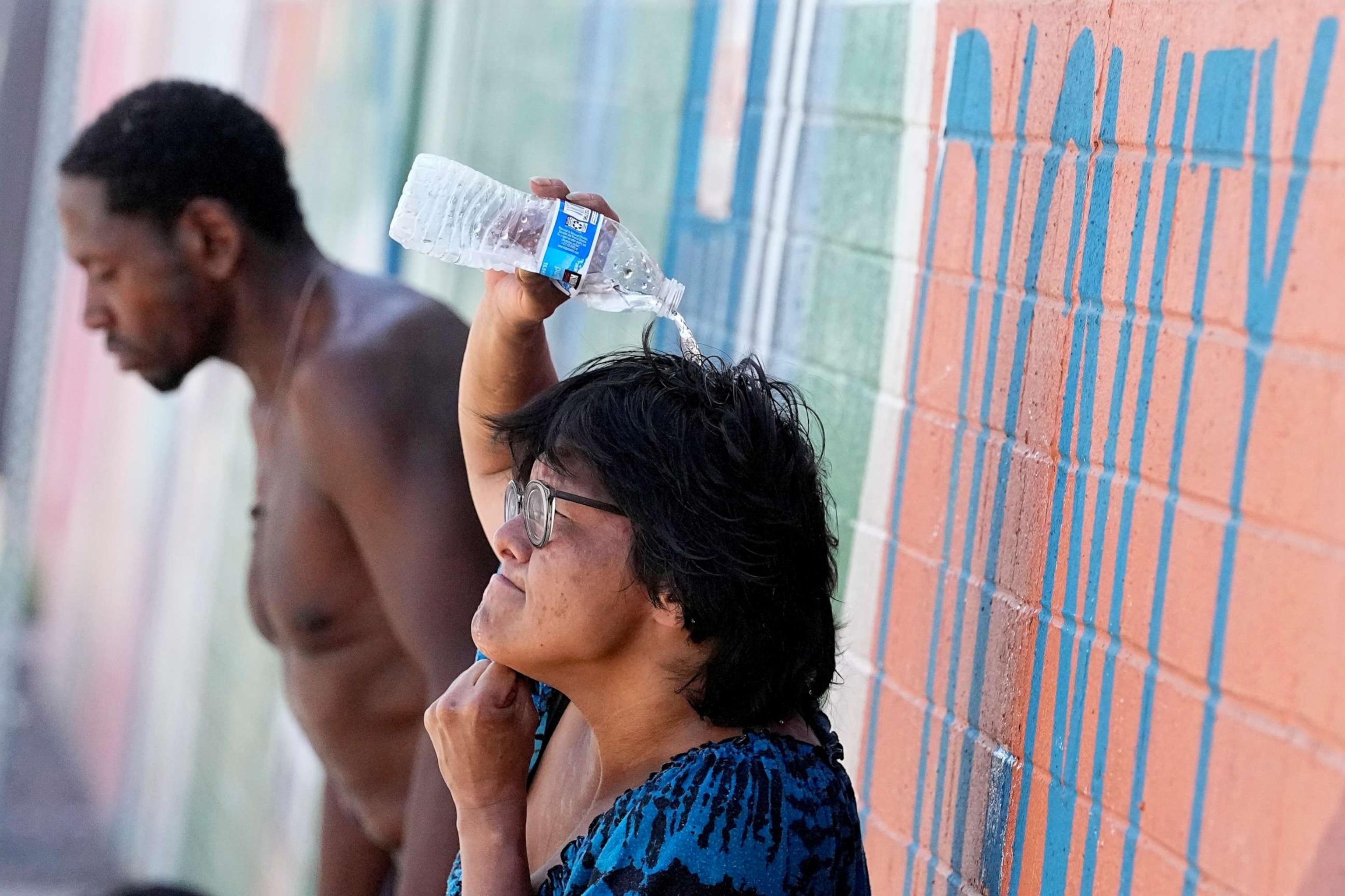 PHOTO: People, who are homeless, try to cool down with chilled water outside the Justa Center, a day center for homeless people 55 years and older, Friday, July 14, 2023, in downtown Phoenix. (AP Photo/Matt York)