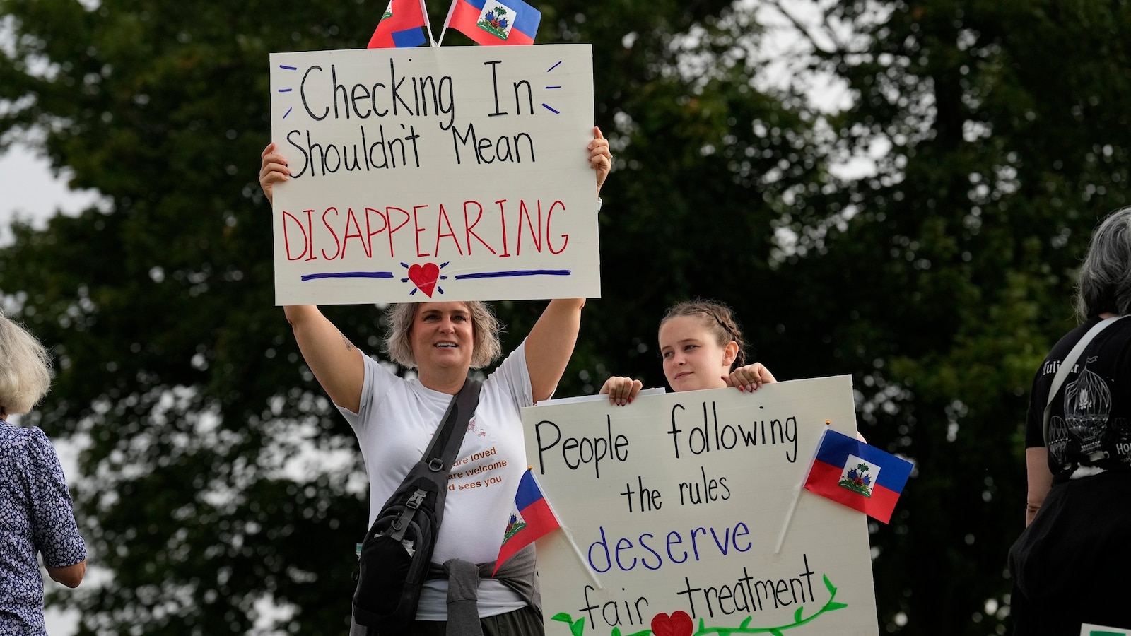 People holding protest signs outdoors.