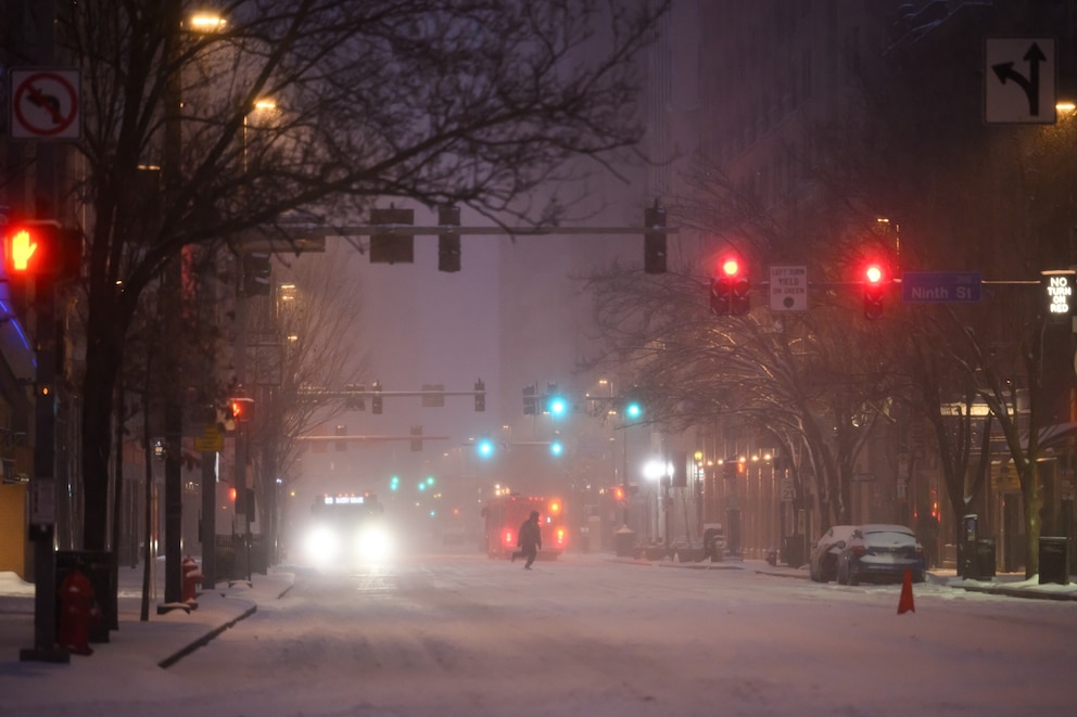 A pedestrian and vehicles during a winter storm in downtown Pittsburgh, Pennsylvania, on Sunday, Jan. 25, 2026. 